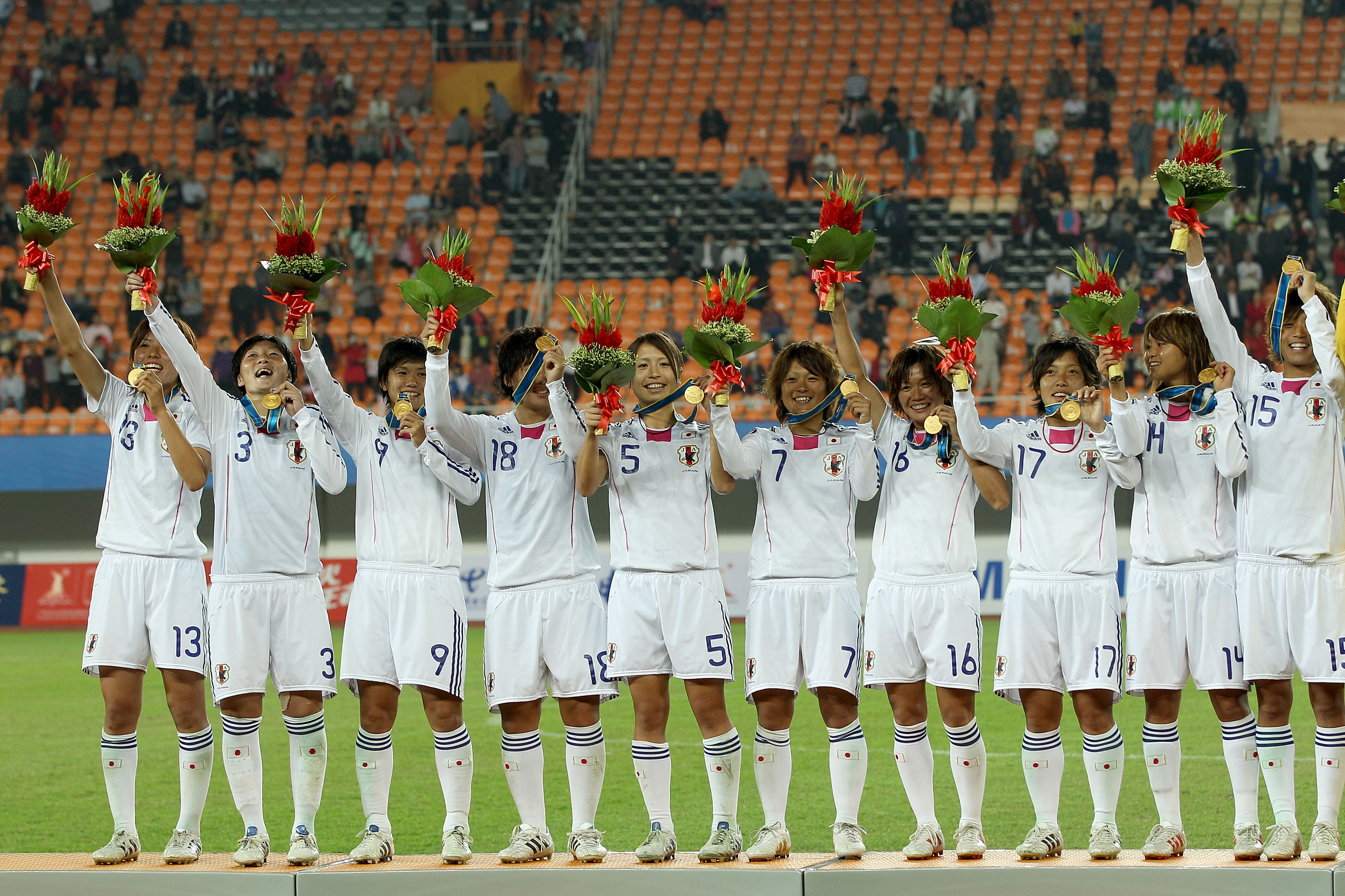 GUANGZHOU, CHINA - NOVEMBER 22:  Japan celebrates on the medal stand after defeating North Korea 1-0 to win the gold medal after the women's gold medal football match at Tianhe Stadium during day ten of the 16th Asian Games Guangzhou 2010 on November 22,