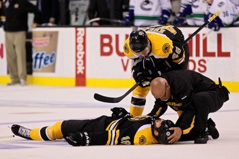 BOSTON, MA - JUNE 06:  David Krejci #46 of the Boston Bruins and a member of the staff check on Nathan Horton #18 after being check by Aaron Rome (not pictured) #29 of the Vancouver Canucks during Game Three of the 2011 NHL Stanley Cup Final at TD Garden 