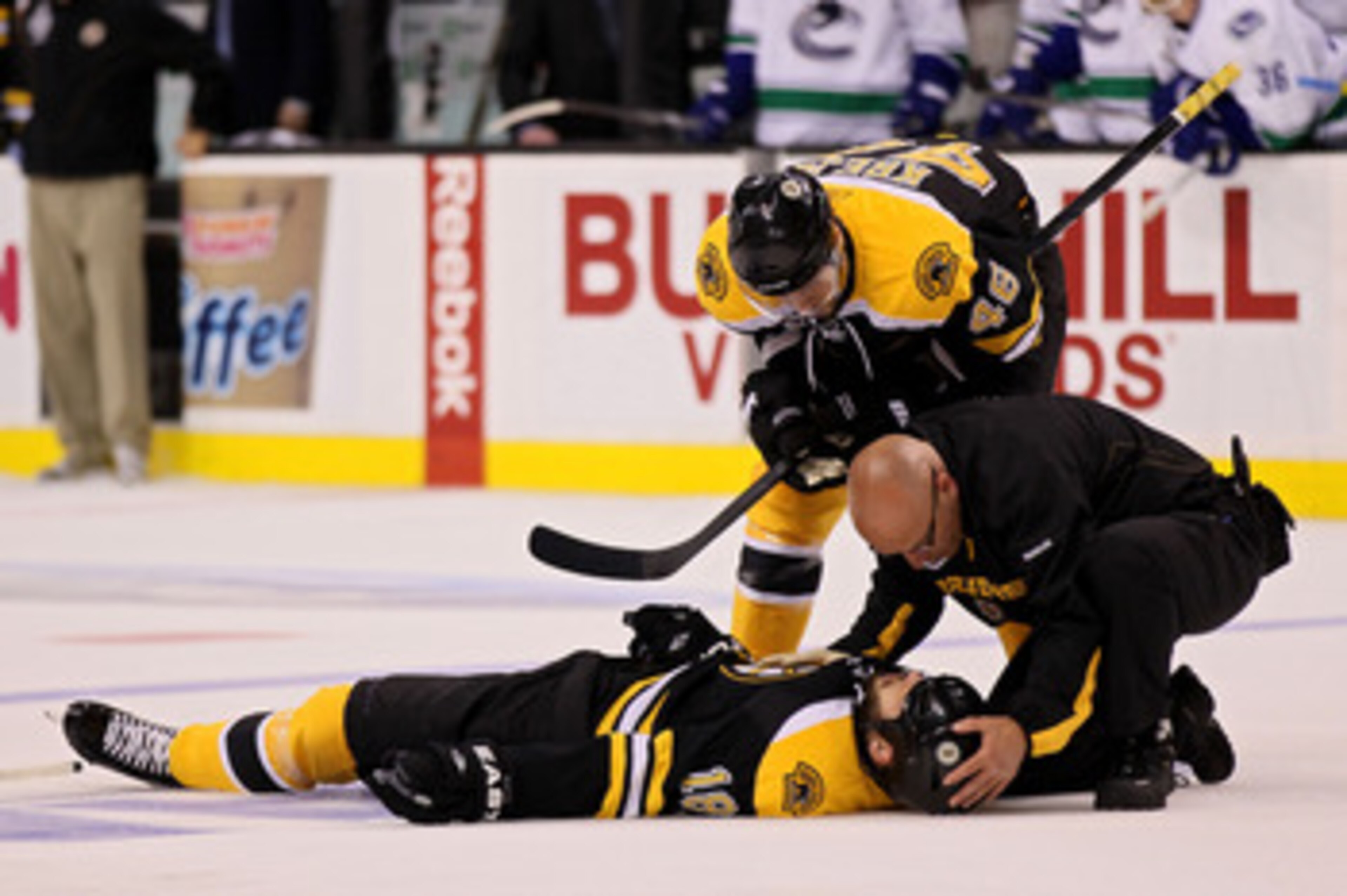 BOSTON, MA - JUNE 06:  David Krejci #46 of the Boston Bruins and a member of the staff check on Nathan Horton #18 after being check by Aaron Rome (not pictured) #29 of the Vancouver Canucks during Game Three of the 2011 NHL Stanley Cup Final at TD Garden 