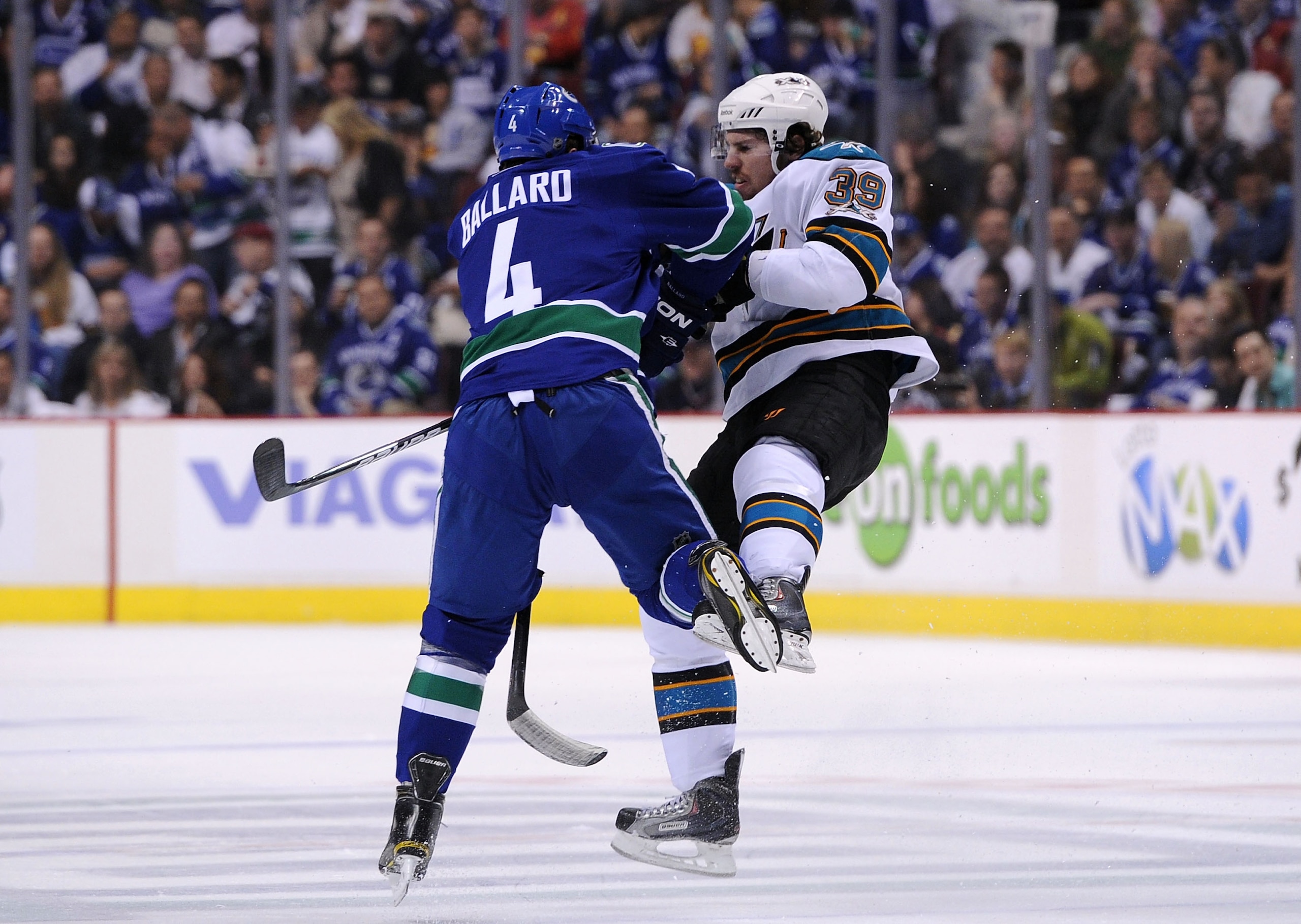 VANCOUVER, CANADA - MAY 24:  Keith Ballard #4 of the Vancouver Canucks checks Logan Couture #39 of the San Jose Sharks in the open ice in Game Five of the Western Conference Finals during the 2011 Stanley Cup Playoffs at Rogers Arena on May 24, 2011 in Va