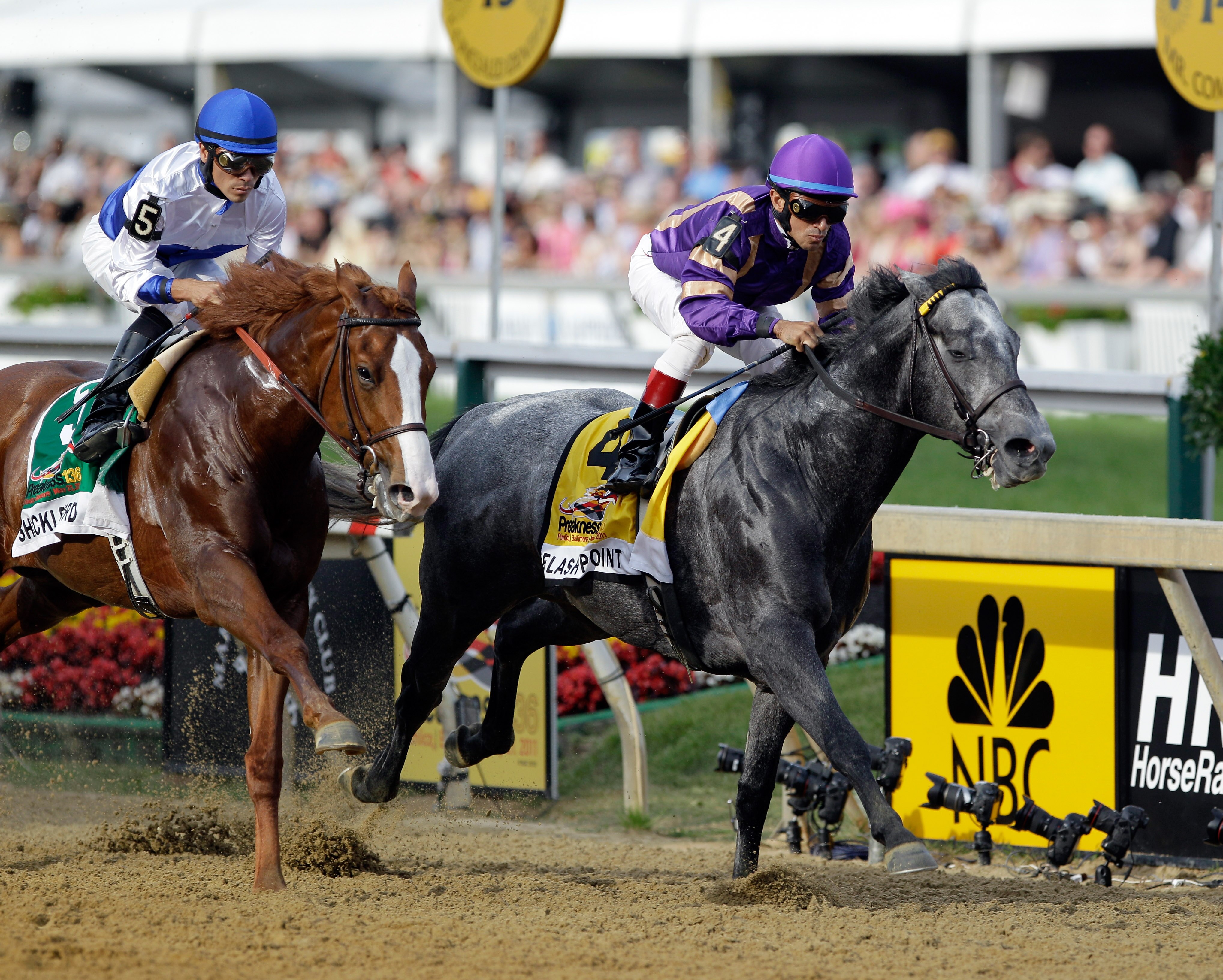 BALTIMORE, MD - MAY 21:  Jockey Jesus Castanon aboard Shackleford #5 (L) and Flashpoint with jockey Cornelio Velasquez #4 (R) in the irons head into the first turn during the 136th running of the Preakness Stakes at Pimlico Race Course on May 21, 2011 in