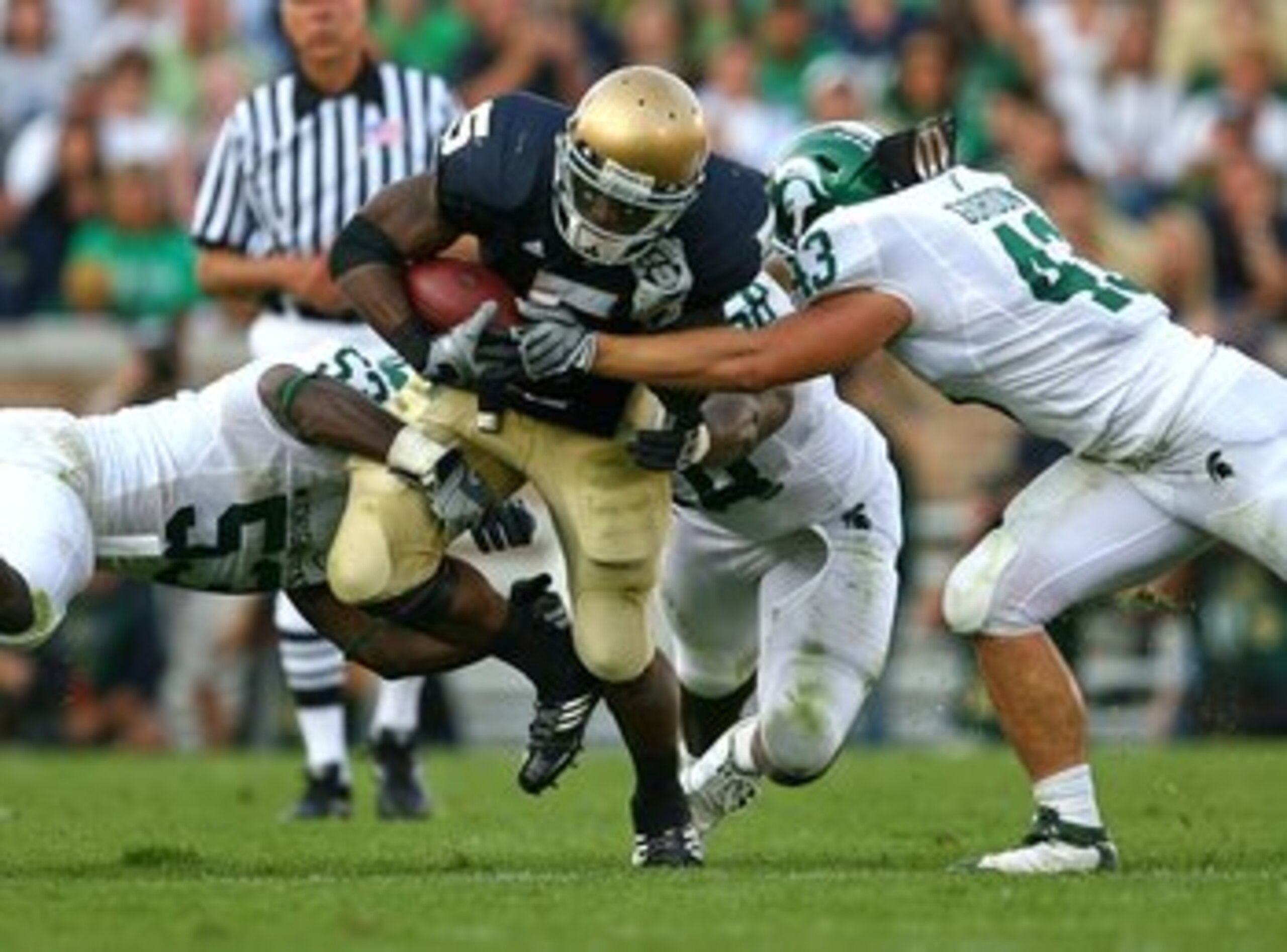 SOUTH BEND, IN - SEPTEMBER 19: Armando Allen #5 of the Notre Dame Fighting Irish is tackled by Greg Jones #53, Trevor Anderson #58 and Eric Gordon #43 of the Michigan State Spartans on September 19, 2009 at Notre Dame Stadium in South Bend, Indiana. Notre