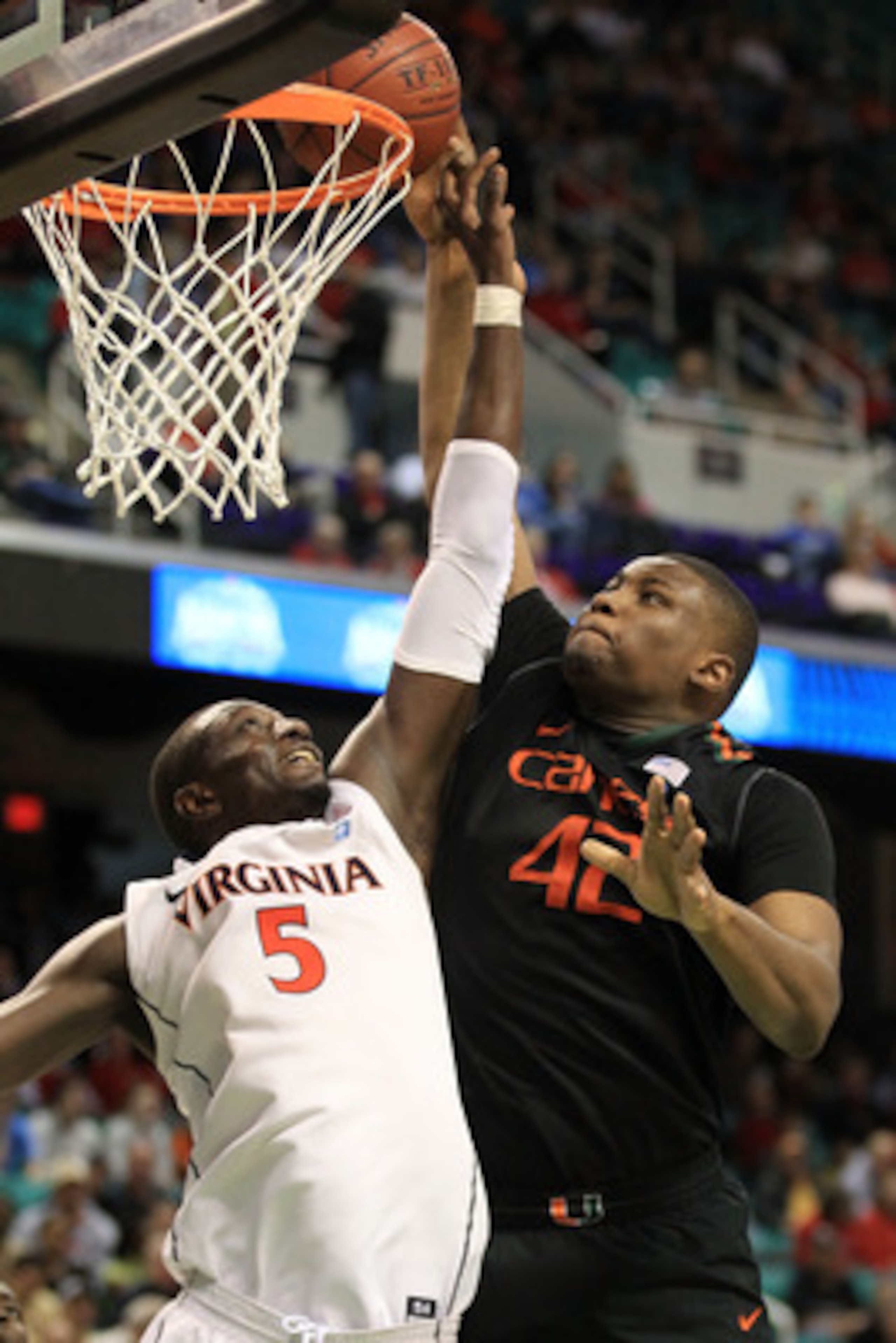 GREENSBORO, NC - MARCH 10:  Reggie Johnson #42 of the Miami Hurricanes shoots against Assane Sene #5 of the Virginia Cavaliers during the second half of the game in the first round of the 2011 ACC men's basketball tournament at the Greensboro Coliseum on