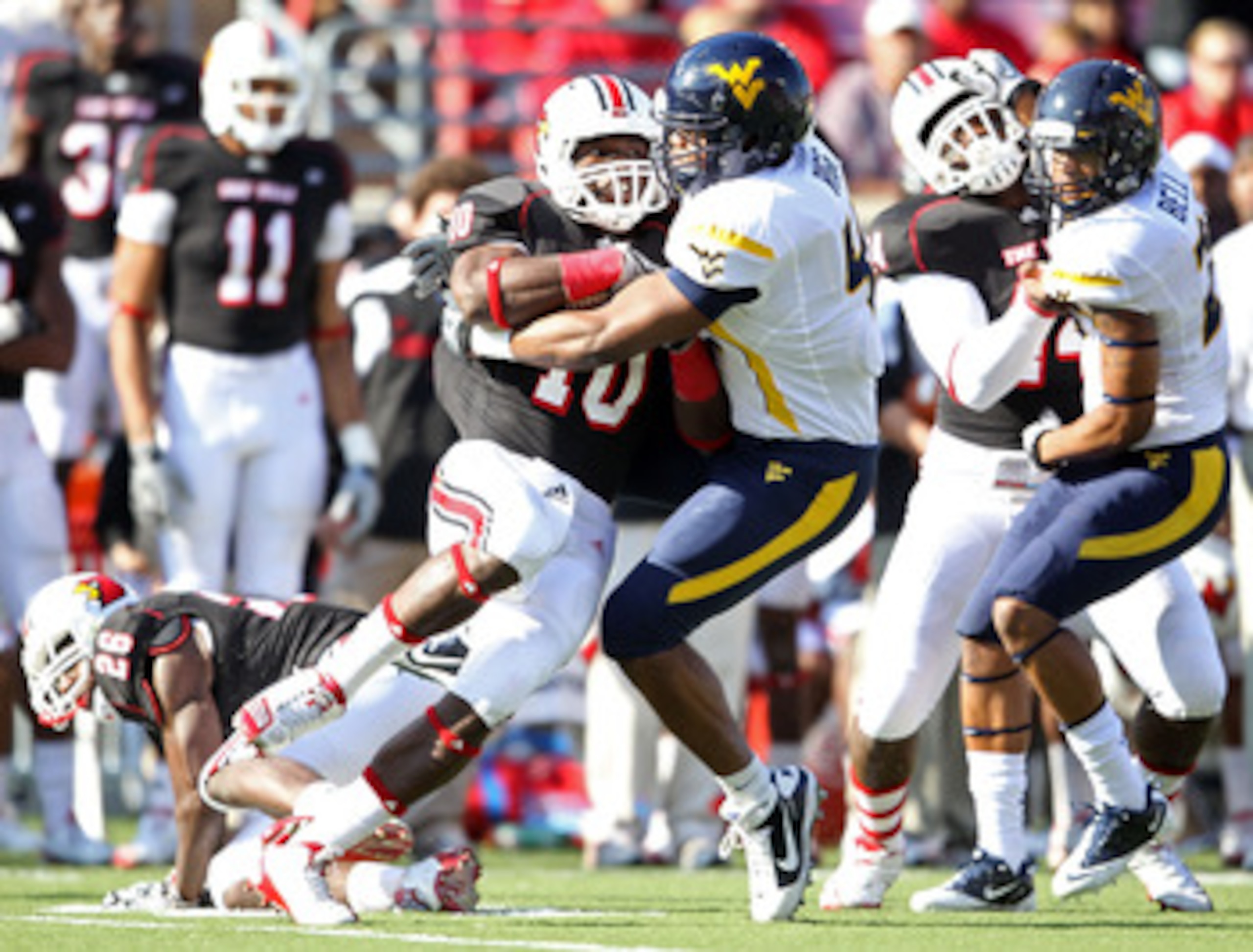 LOUISVILLE, KY - NOVEMBER 20:  Dominique Brown #10 of the Louisville Cardinals is tackled by Doug Rigg #47 of the West Virginia Mountaineers during the game at Papa John's Cardinal Stadium on November 20, 2010 in Louisville, Kentucky.  (Photo by Andy Lyon