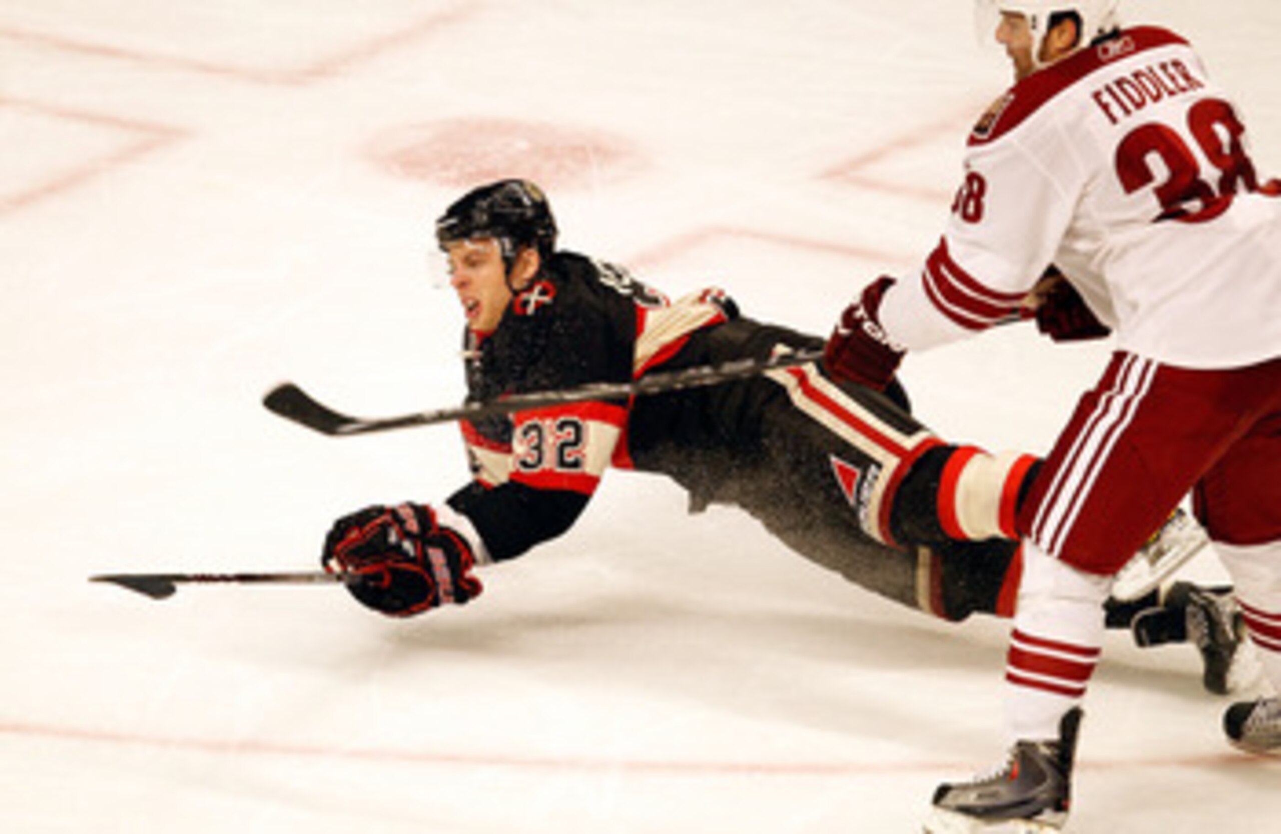 CHICAGO - MARCH 23: Kris Versteeg #32 of the Chicago Blackhawks hits the ice in front of Vernon Fiddler #38 of the Phoenix Coyotes after being hooked in the third period at the United Center on March 23, 2010 in Chicago, Illinois. The Blackhawks defeated