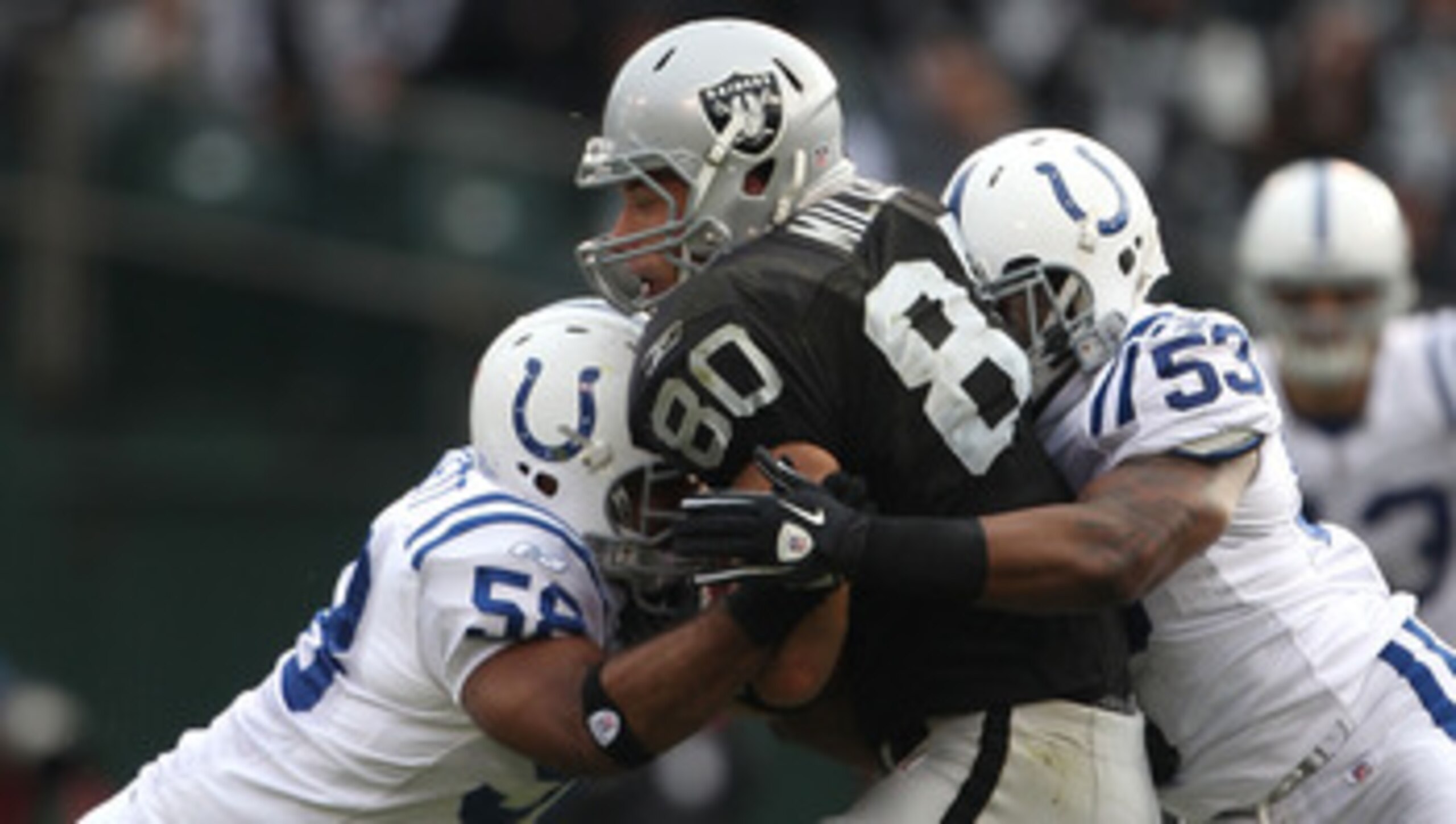 OAKLAND, CA - DECEMBER 26: Kavell Conner #53 and Tyjuan Hagler #56 of the Indianapolis Colts tackle Zach Miller #80 of the Oakland Raiders during an NFL game at Oakland-Alameda County Coliseum on December  26, 2010 in Oakland, California.  (Photo by Jed J