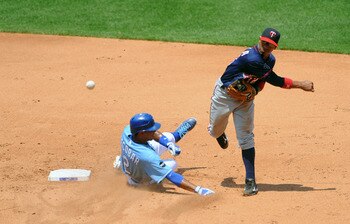 KANSAS CITY, MO - JUNE 5: Alexi Casilla #12 of the Minnesota Twins  throws to first base to complete a double play as Alcides Escobar #2 of the Kansas City Royals slides in at Kauffman Stadium on June 5, 2011 in Kansas City, Missouri. (Photo by G. Newman