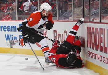 NEWARK, NJ - OCTOBER 24:  Scottie Upshall #9 of the Philadelphia Flyers hits Andy Greene #6 of the New Jersey Devils into the boards on October 24, 2008 at the Prudential Center in Newark, New Jersey.  (Photo by Bruce Bennett/Getty Images)