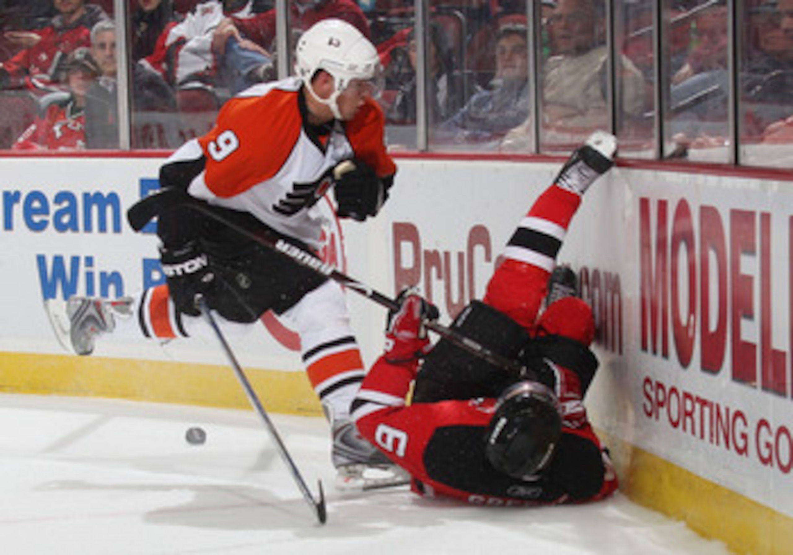 NEWARK, NJ - OCTOBER 24:  Scottie Upshall #9 of the Philadelphia Flyers hits Andy Greene #6 of the New Jersey Devils into the boards on October 24, 2008 at the Prudential Center in Newark, New Jersey.  (Photo by Bruce Bennett/Getty Images)