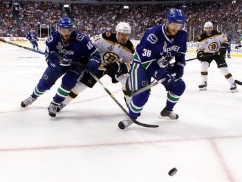 VANCOUVER, BC - JUNE 04:  Maxim Lapierre #40 and Jannik Hansen #36 of the Vancouver Canucks skate for the puck against Andrew Ference #21 of the Boston Bruins during Game Two of the 2011 NHL Stanley Cup Final at Rogers Arena on June 4, 2011 in Vancouver, 