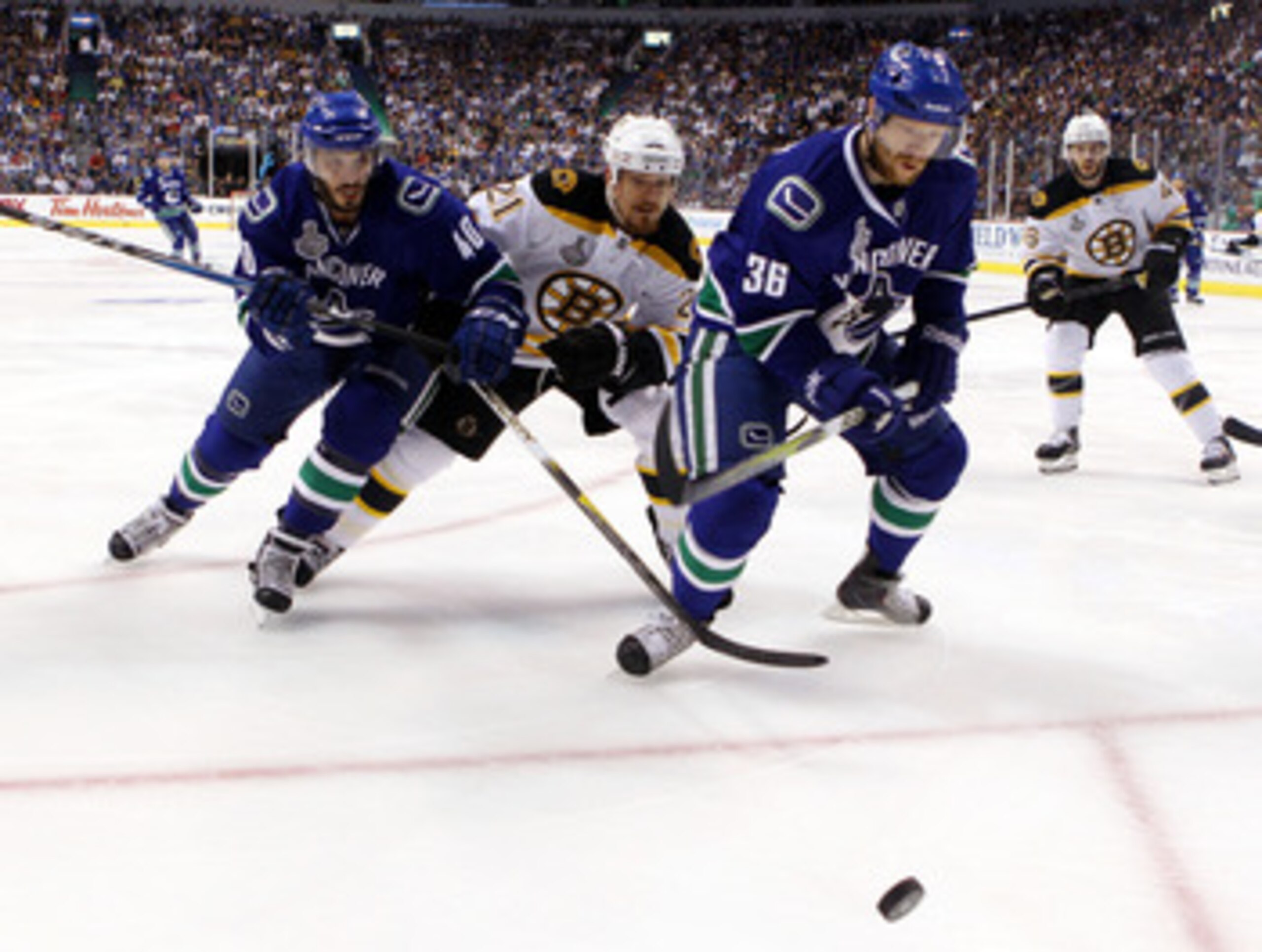 VANCOUVER, BC - JUNE 04:  Maxim Lapierre #40 and Jannik Hansen #36 of the Vancouver Canucks skate for the puck against Andrew Ference #21 of the Boston Bruins during Game Two of the 2011 NHL Stanley Cup Final at Rogers Arena on June 4, 2011 in Vancouver, 