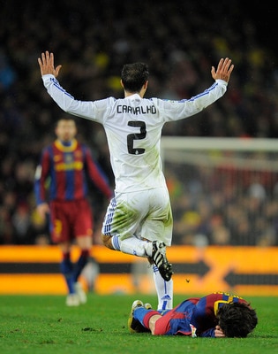 BARCELONA, SPAIN - NOVEMBER 29:  Lionel Messi of Barcelona (R) lays on the pitch after being hit by Ricardo Carvalho of Real Madrid during the La Liga match between Barcelona and Real Madrid at the Camp Nou Stadium on November 29, 2010 in Barcelona, Spain