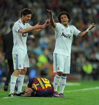 MADRID, SPAIN - APRIL 16: Xabi Alonso (L) and Marcelo of Real Madrid react after Sergio Busquets of Barcelona took a knock during the La Liga match between Real Madrid and Barcelona at Estadio Santiago Bernabeu on April 16, 2011 in Madrid, Spain.  (Photo