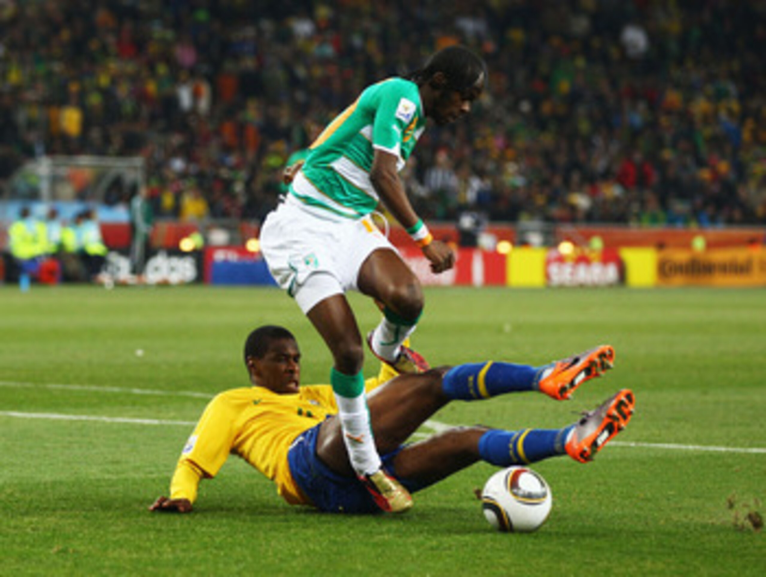 JOHANNESBURG, SOUTH AFRICA - JUNE 20: Juan of Brazil tackles Gervinho of Ivory Coast during the 2010 FIFA World Cup South Africa Group G match between Brazil and Ivory Coast at Soccer City Stadium on June 20, 2010 in Johannesburg, South Africa.  (Photo by