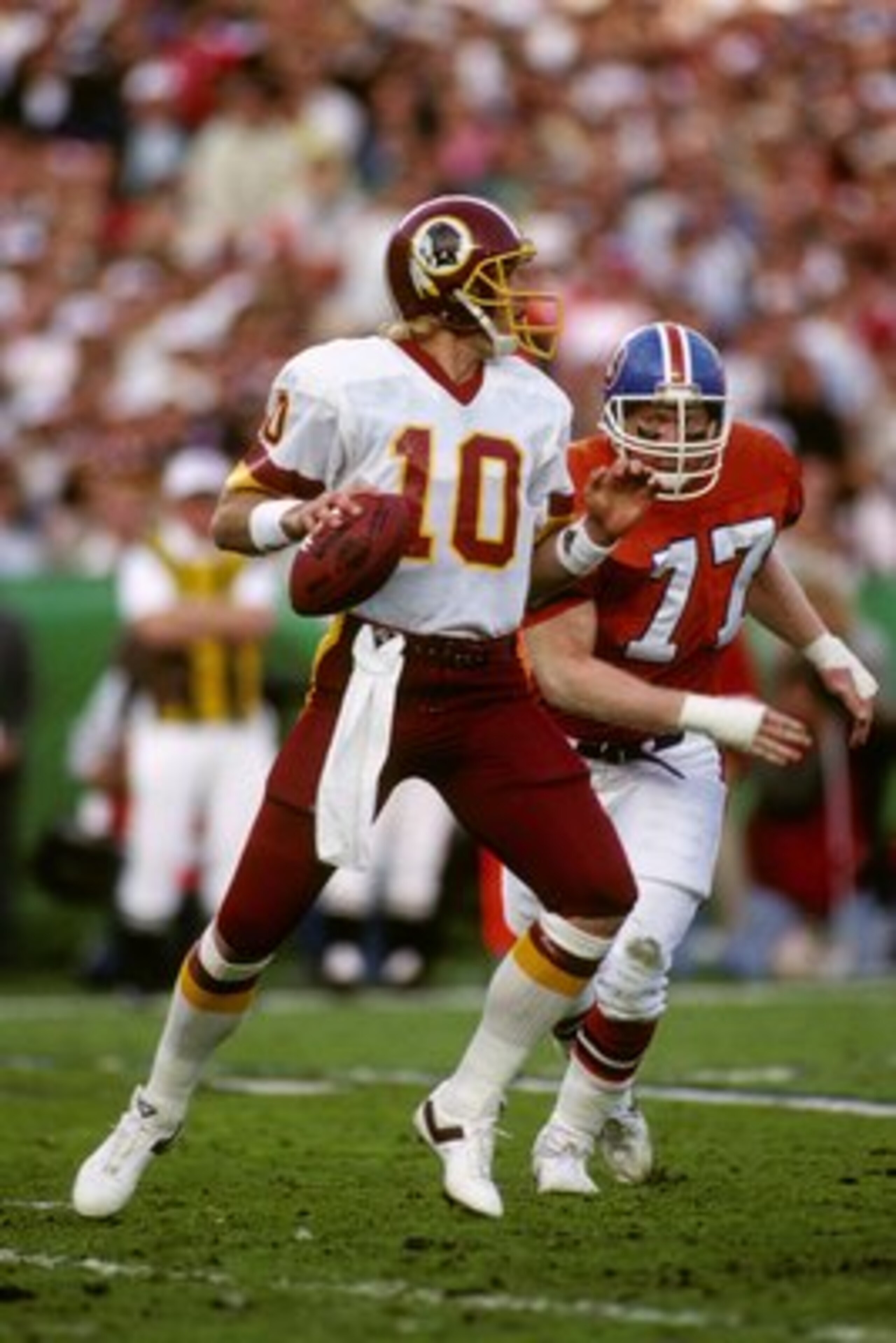 SAN DIEGO - JANUARY 31:  Quarterback Jay Schroeder #10 of the Washington Redskins drops back to pass under pressure from defensive end Karl Mecklenburg #77 of the Denver Broncos during Super Bowl XXII at Jack Murphy Stadium on January 31, 1988 in San Dieg