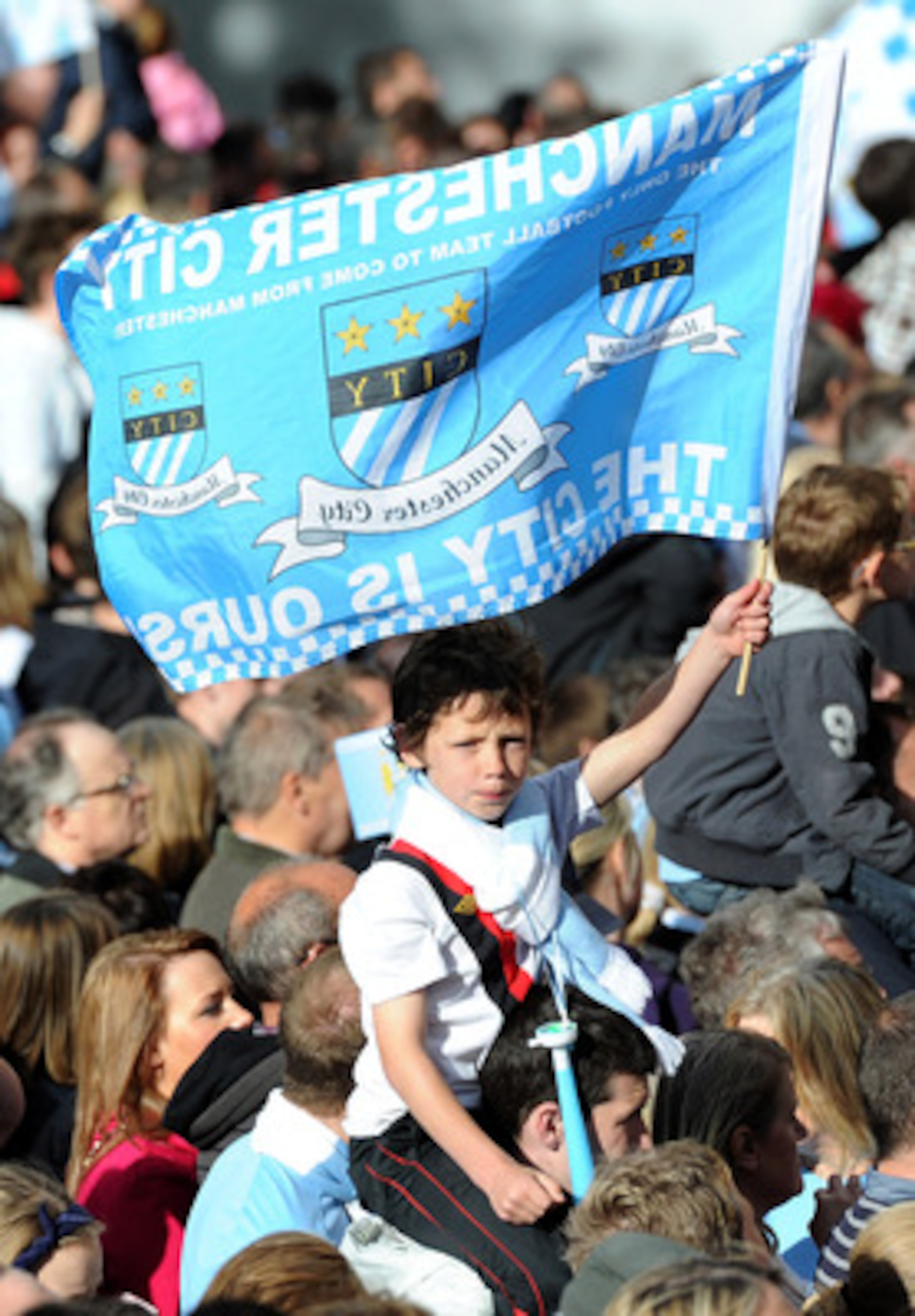 MANCHESTER, ENGLAND - MAY 23:  A young Manchester City fan waves a flag during the Manchester City FA Cup Winners Parade at Manchester Town Hall on May 23, 2011 in Manchester, United Kingdom.  (Photo by Chris Brunskill/Getty Images)