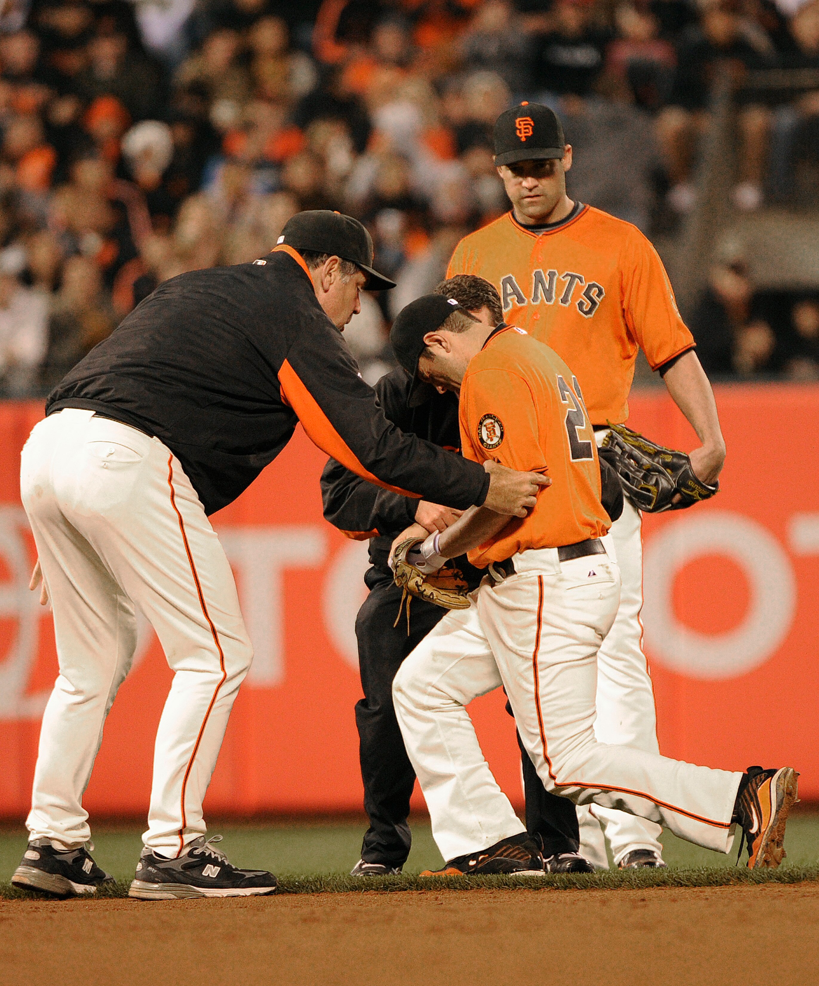 SAN FRANCISCO, CA - JUNE 10: Manager Bruce Bochy (L) of the San Francisco Giants helps injured second baseman Freddy Sanchez #21 up and off the field as Pat Burrell #5 looks on against the Cincinnati Reds during a MLB baseball game June 10, 2011 at AT&T P