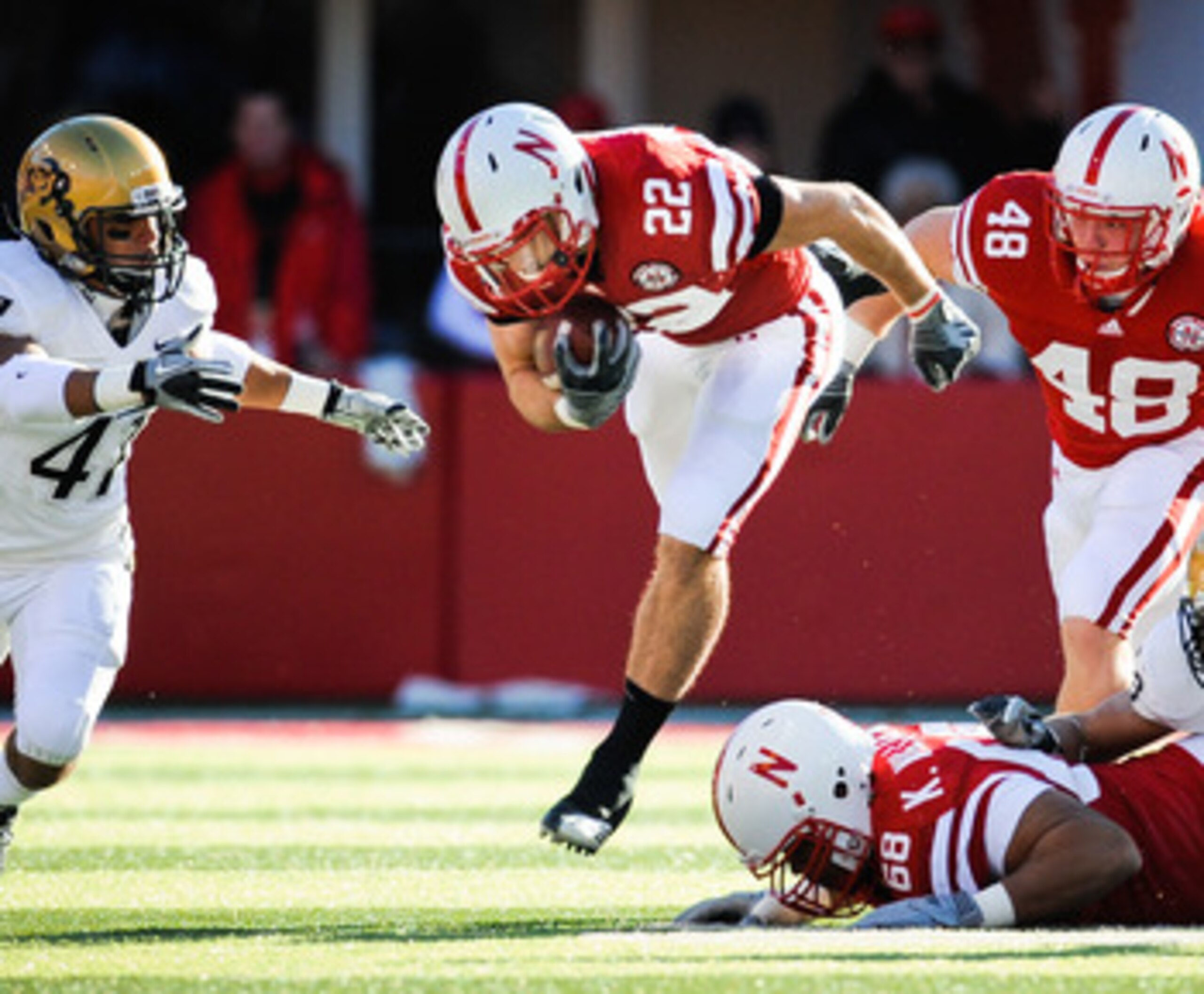 LINCOLN, NE - NOVEMBER 26: Rex Burkhead #22 of the Nebraska Cornhuskers leaps over teammate Keith Williams #68 and is helped by Tyler Legate #48 and Kyler Reed #25 of the Nebraska Cornhuskers during their game against the Colorado Buffaloes at Memorial St