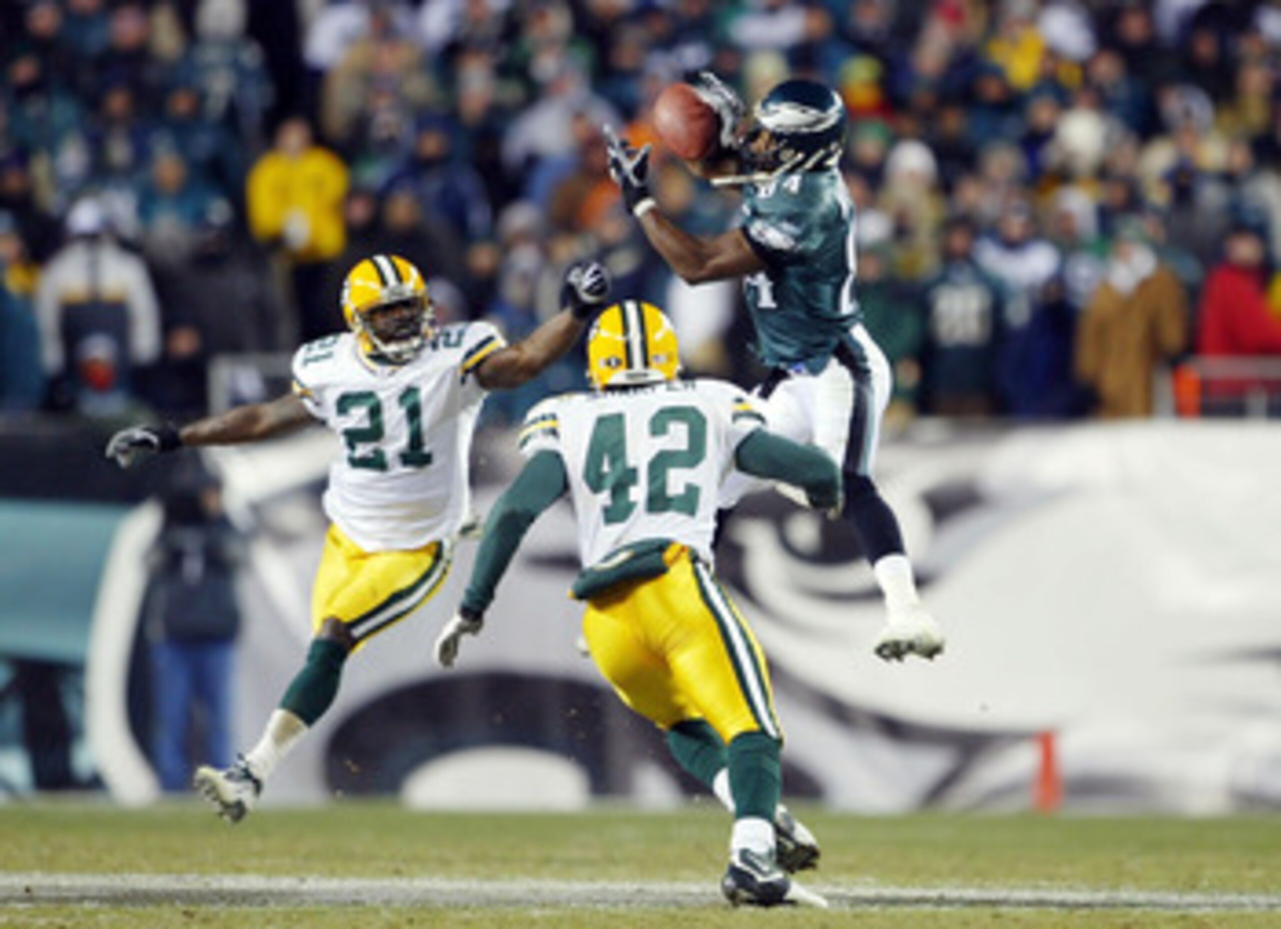 PHILADELPHIA - JANUARY 11:  Wide receiver Freddie Mitchell #84 of the Philadelphia Eagles catches a 28-yard catch on defensive backs Jue Bhawoh #21 and Darren Sharper #42 of the Green Bay Packers on the Eagles last posession in the forth quarter during th
