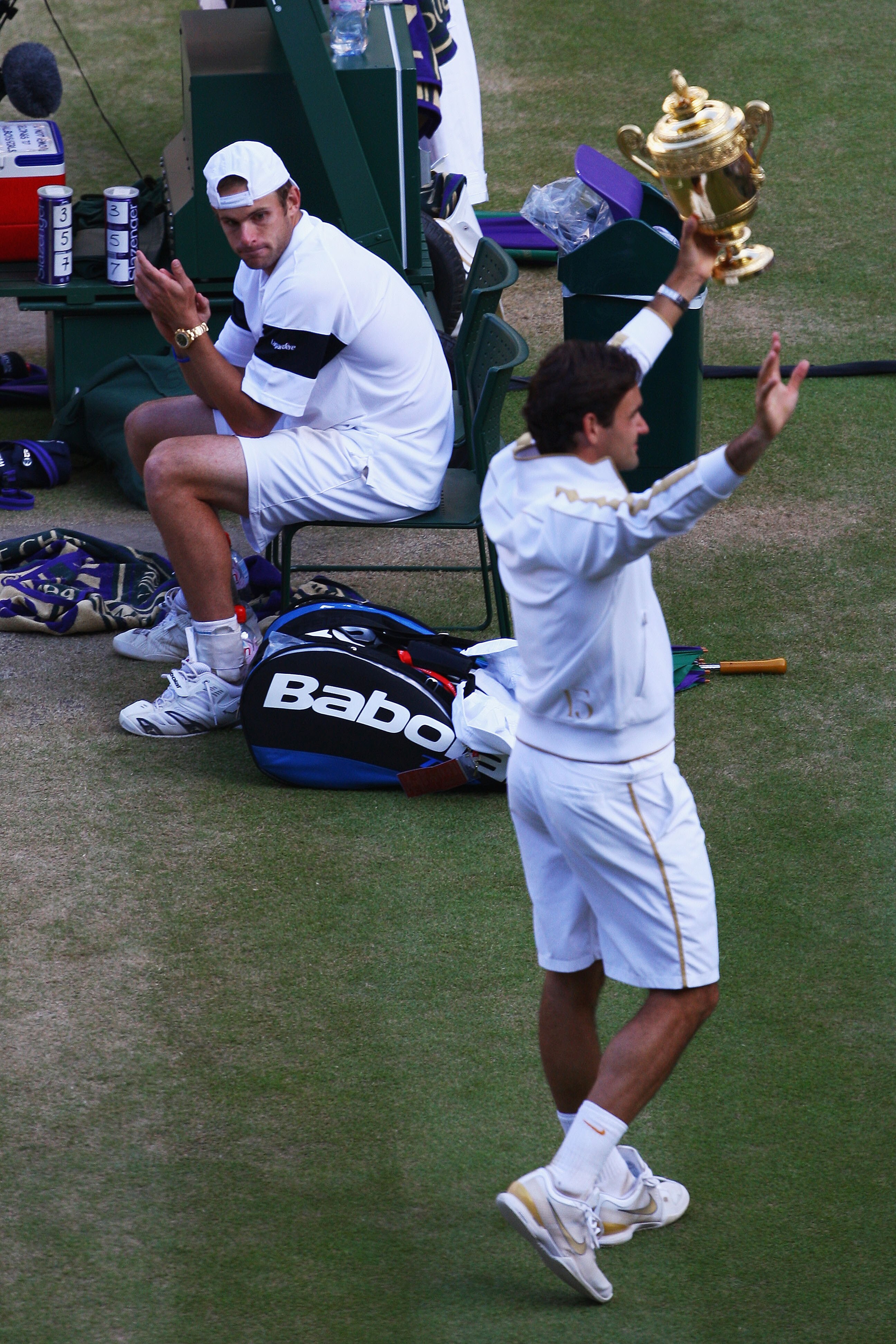 WIMBLEDON, ENGLAND - JULY 05:  Andy Roddick of USA looks despondent as Roger Federer of Switzerland celebrates with the trophy during the men's singles final match on Day Thirteen of the Wimbledon Lawn Tennis Championships at the All England Lawn Tennis a