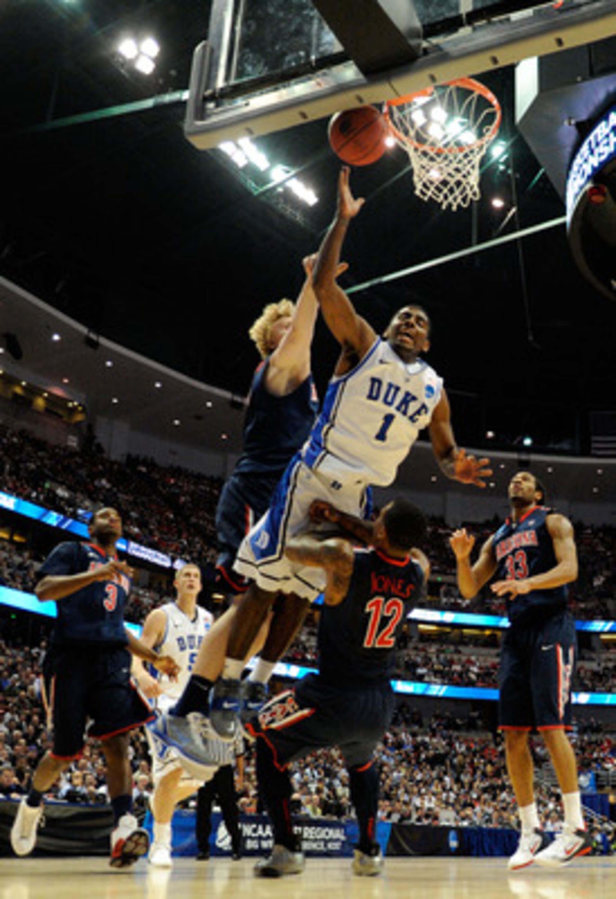 ANAHEIM, CA - MARCH 24:  Kyrie Irving #1 of the Duke Blue Devils draws contact against Kyryl Natyazhko #1 and Lamont Jones #12 of the Arizona Wildcats during the west regional semifinal of the 2011 NCAA men's basketball tournament at the Honda Center on M