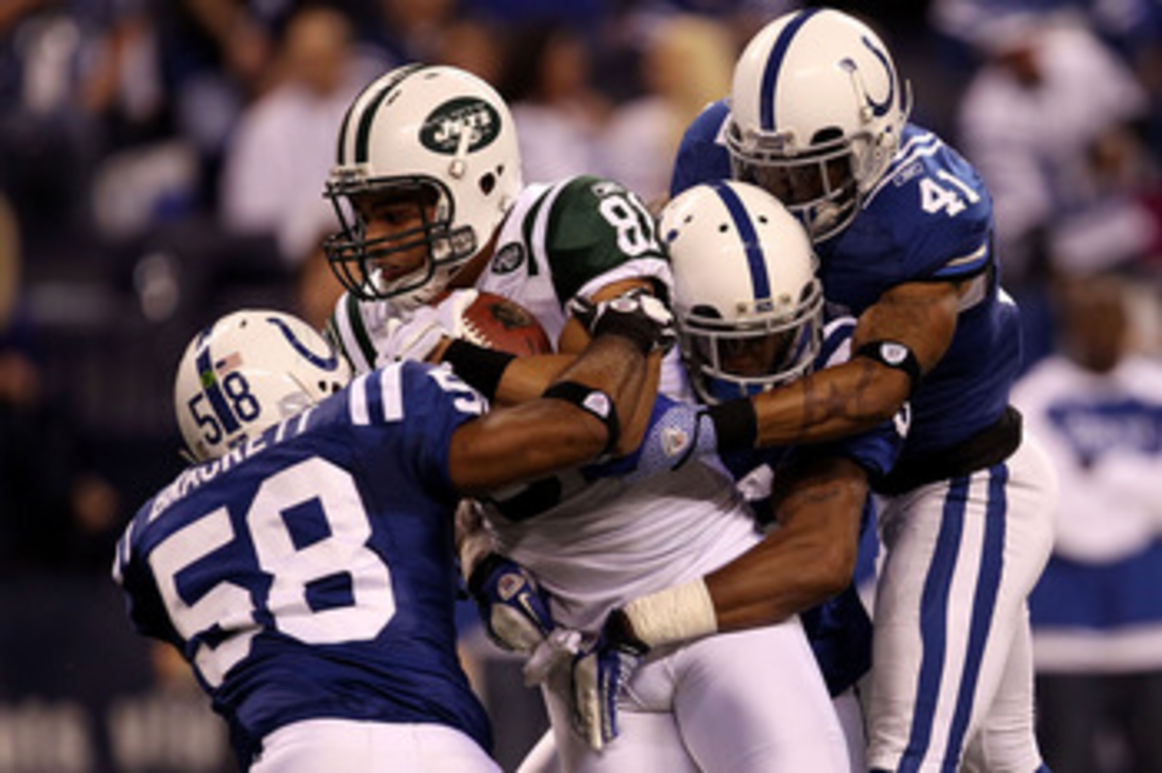 INDIANAPOLIS, IN - JANUARY 08:  Dustin Keller #81 of the New York Jets makes a reception against Gary Brackett #58 amd Antoine Bethea #41 of the Indianapolis Colts during their 2011 AFC wild card playoff game at Lucas Oil Stadium on January 8, 2011 in Ind