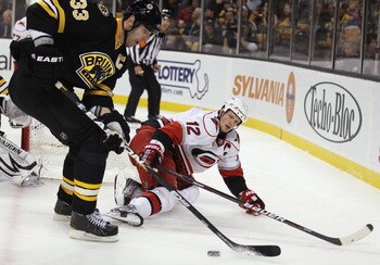 BOSTON - NOVEMBER 26:  Zdeno Chara #33 of the Boston Bruins takes the puck from Eric Staal #12 of the Carolina Hurricanes on November 26, 2010 at the TD Garden in Boston, Massachusetts.  (Photo by Elsa/Getty Images)