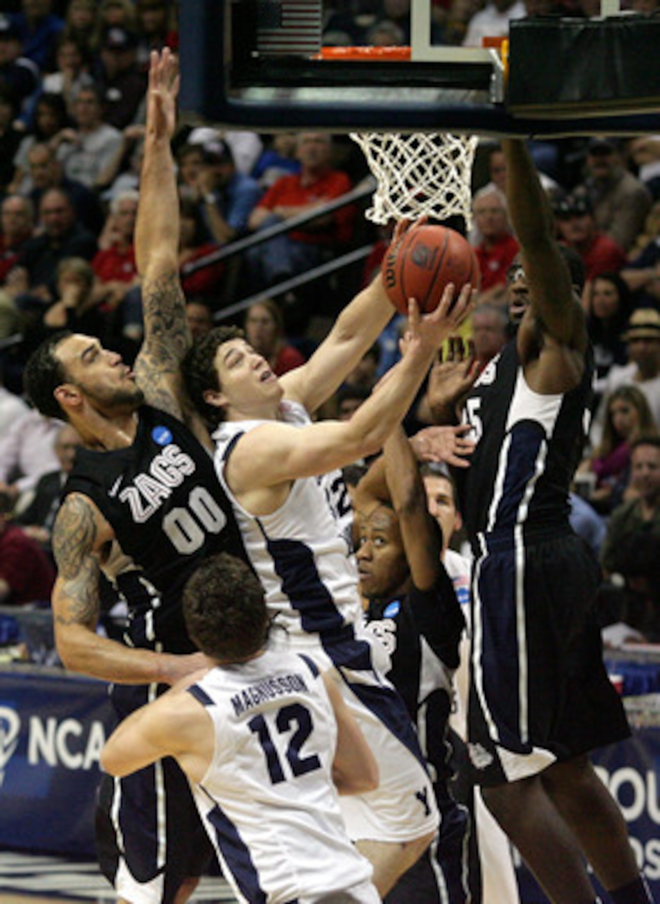 DENVER, CO - MARCH 19:  Jimmer Fredette #32 of the Brigham Young Cougars goes to the hoop against Robert Sacre #00 and Sam Dower #35 of the Gonzaga Bulldogs during the third round of the 2011 NCAA men's basketball tournament at Pepsi Center on March 19, 2
