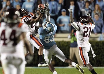 CHAPEL HILL, NC - NOVEMBER 13:  Jayron Hosley #20 of the Virginia Tech Hokies makes an interception as teammate Rashad Carmichael #21 watches on with Dwight Jones #83 of the North Carolina Tar Heels during their game at Kenan Stadium on November 13, 2010
