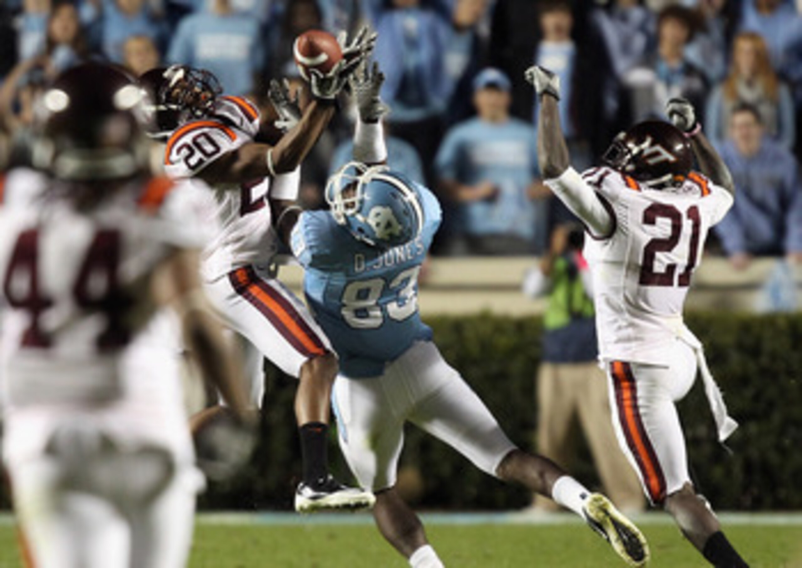 CHAPEL HILL, NC - NOVEMBER 13:  Jayron Hosley #20 of the Virginia Tech Hokies makes an interception as teammate Rashad Carmichael #21 watches on with Dwight Jones #83 of the North Carolina Tar Heels during their game at Kenan Stadium on November 13, 2010