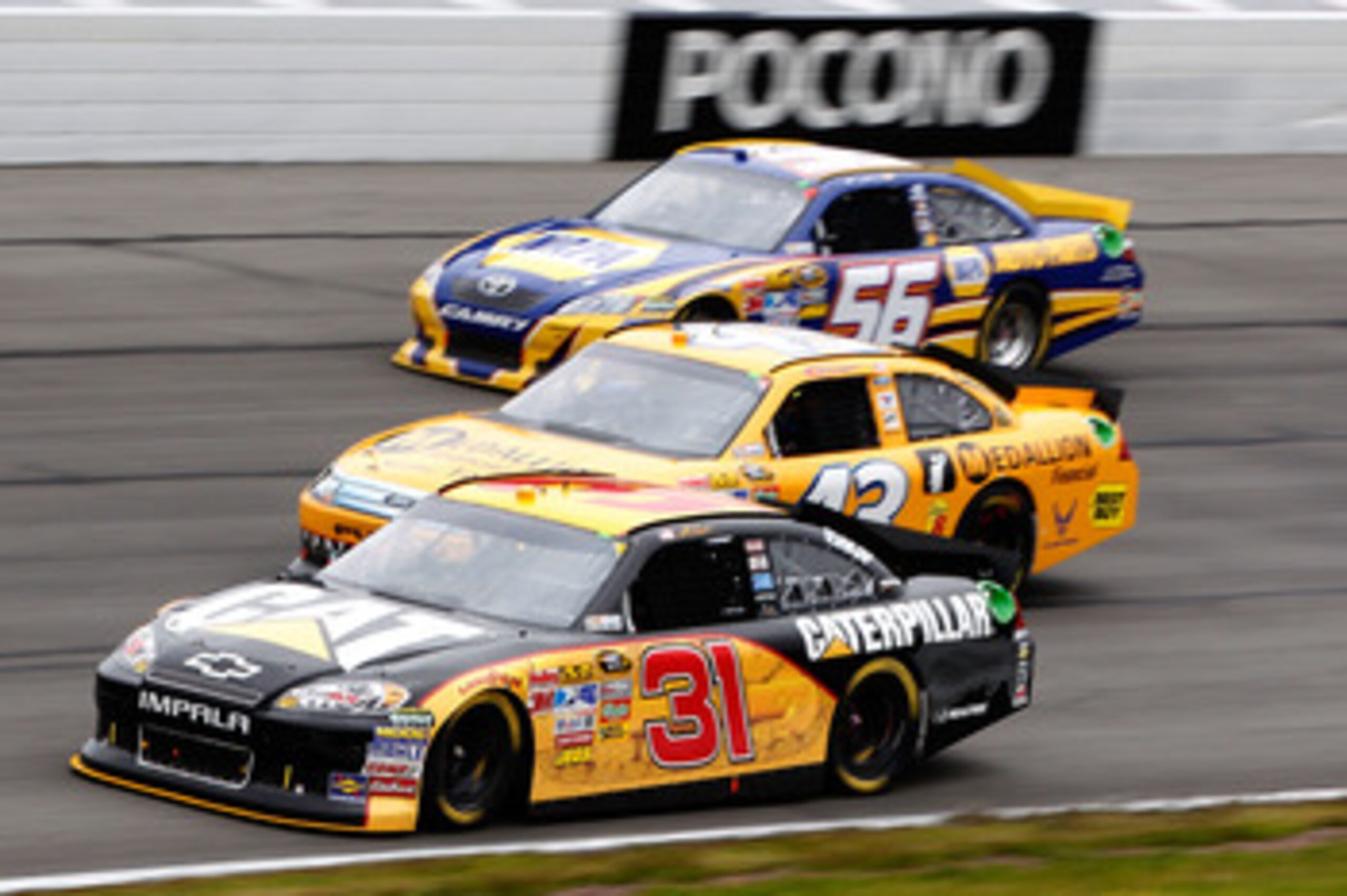 LONG POND, PA - JUNE 12:  Jeff Burton, driver of the #31 Caterpillar Chevrolet, A.J. Allmendinger, driver of the #43 Medallion Financial Ford, and Martin Truex Jr., driver of the #56 NAPA Auto Parts Toyota, race during the NASCAR Sprint Cup Series 5-Hour 