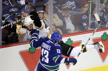 VANCOUVER, BC - JUNE 10:  Johnny Boychuk #55 of the Boston Bruins draws contanct against Raffi Torres #13 of the Vancouver Canucks during Game Five of the 2011 NHL Stanley Cup Final at Rogers Arena on June 10, 2011 in Vancouver, British Columbia, Canada. 