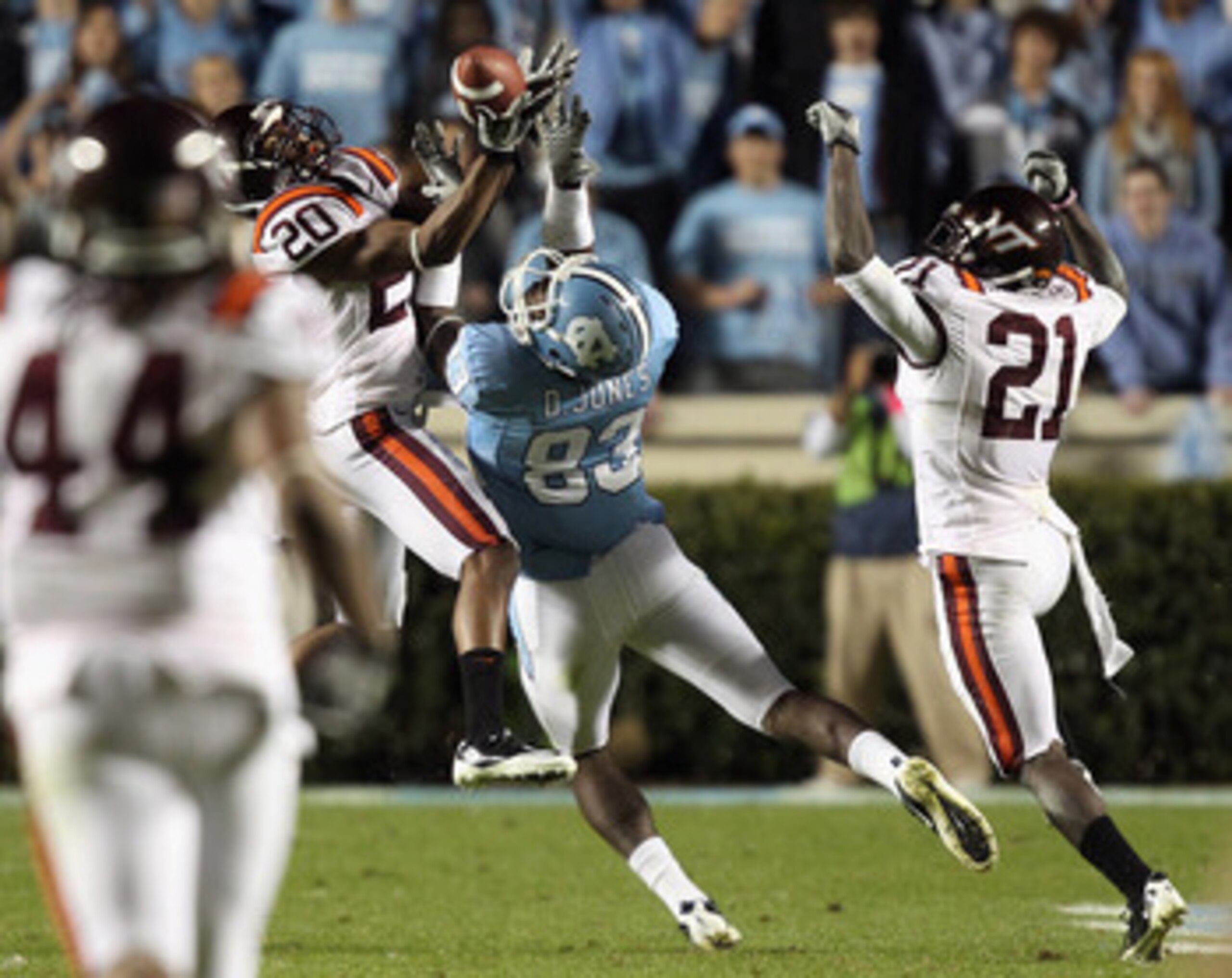 CHAPEL HILL, NC - NOVEMBER 13:  Jayron Hosley #20 of the Virginia Tech Hokies makes an interception as teammate Rashad Carmichael #21 watches on with Dwight Jones #83 of the North Carolina Tar Heels during their game at Kenan Stadium on November 13, 2010 