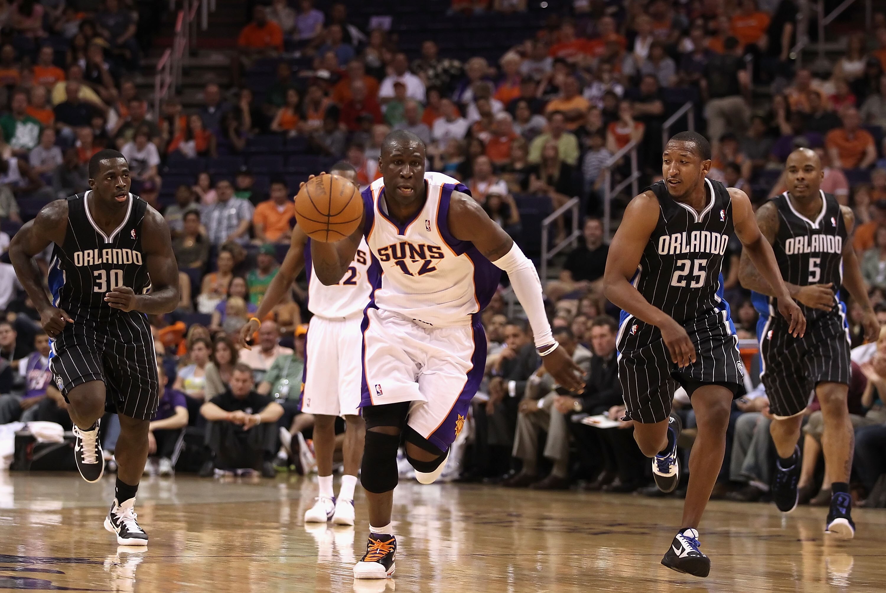 PHOENIX, AZ - MARCH 13:  Mickael Pietrus #12 of the Phoenix Suns moves the ball upcourt past Brandon Bass #30 and Chris Duhon #25 of the Orlando Magic during the NBA game at US Airways Center on March 13, 2011 in Phoenix, Arizona. The Magic defeated the S