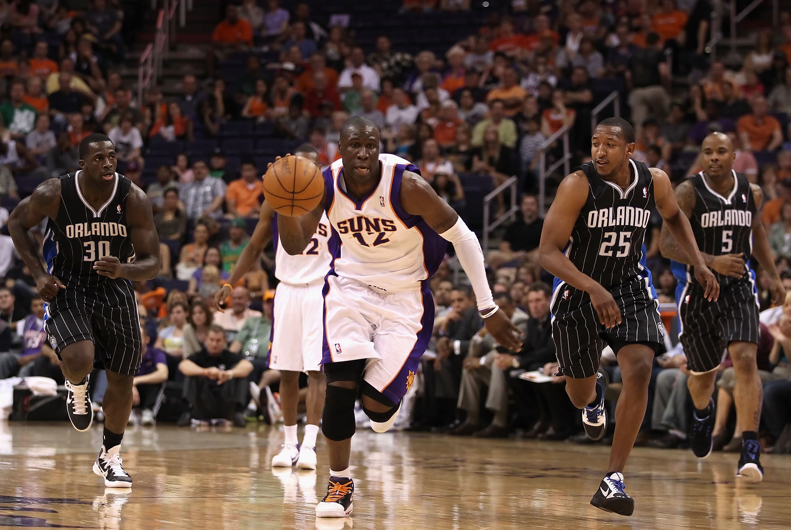 PHOENIX, AZ - MARCH 13:  Mickael Pietrus #12 of the Phoenix Suns moves the ball upcourt past Brandon Bass #30 and Chris Duhon #25 of the Orlando Magic during the NBA game at US Airways Center on March 13, 2011 in Phoenix, Arizona. The Magic defeated the S