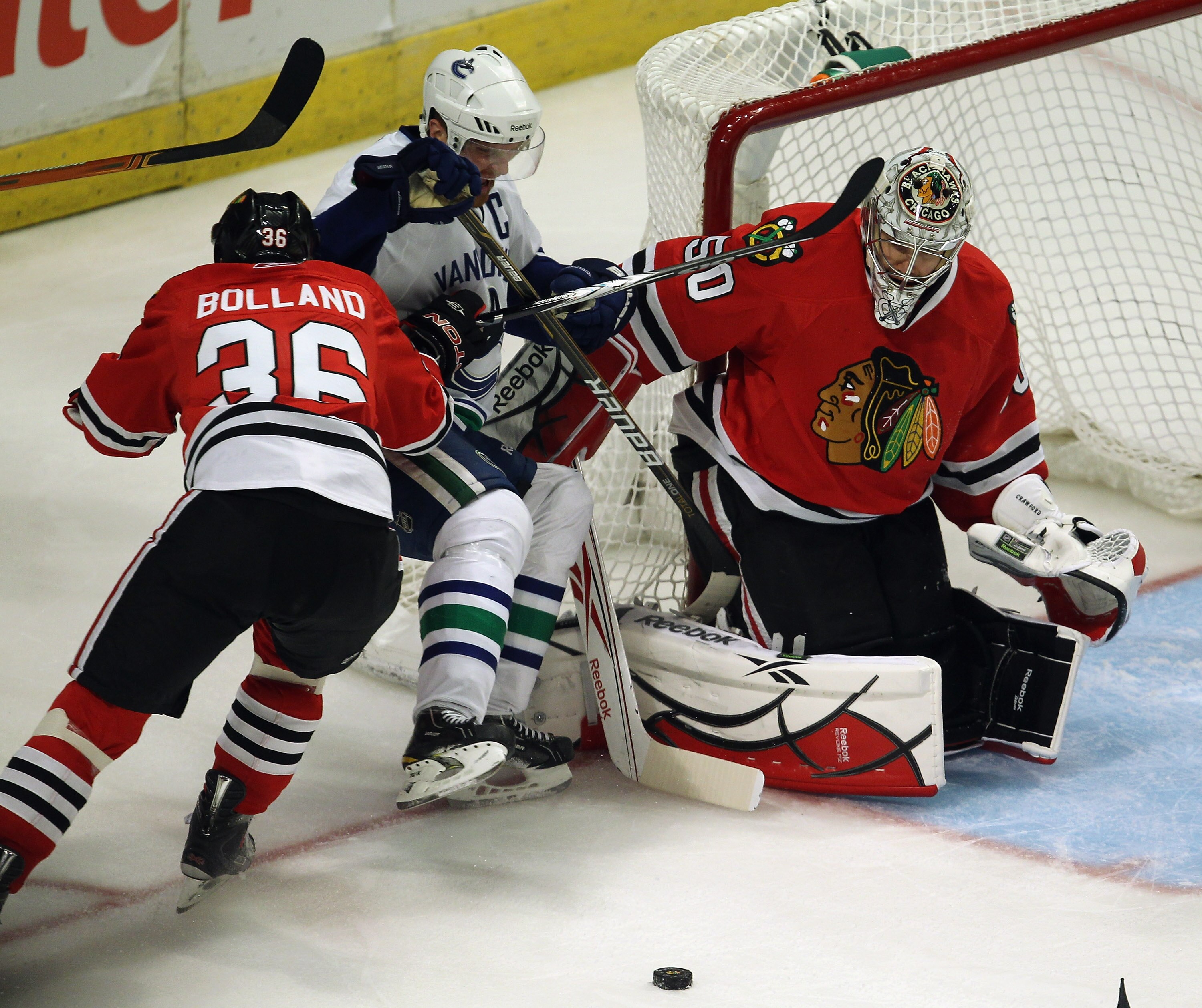 CHICAGO, IL - APRIL 24: Dave Bolland #36 of the Chicago Blackhawks knocks down Henrik Sedin #33 of the Vancouver Canucks as Corey Crawford #50 rejects a shot in Game Six of the Western Conference Quarterfinals during the 2011 NHL Stanley Cup Playoffs at t