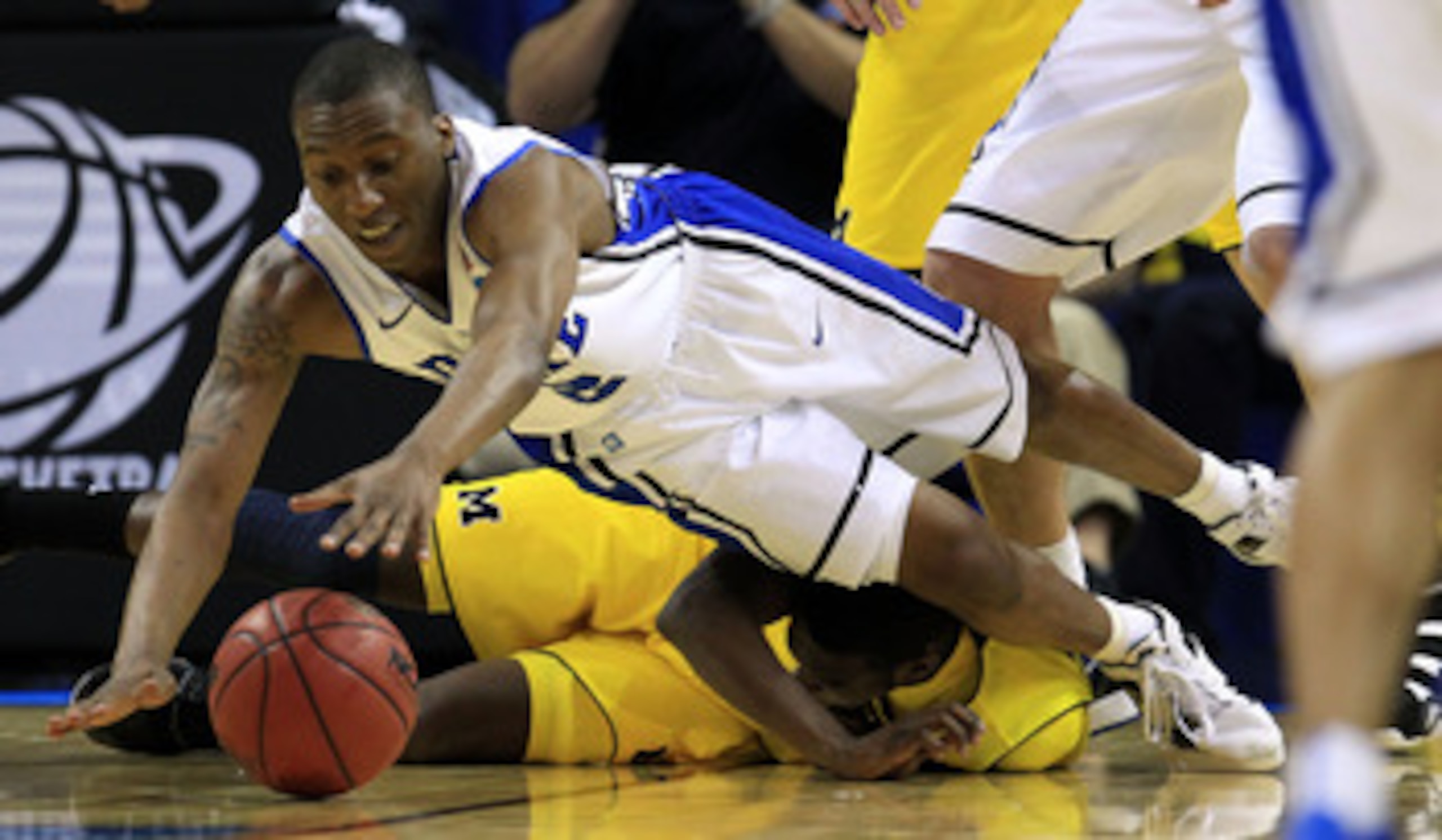 CHARLOTTE, NC - MARCH 20:  Nolan Smith #2 of the Duke Blue Devils dives for the ball over Tim Hardaway Jr. #10 of the Michigan Wolverines in the first half during the third round of the 2011 NCAA men's basketball tournament at Time Warner Cable Arena on M