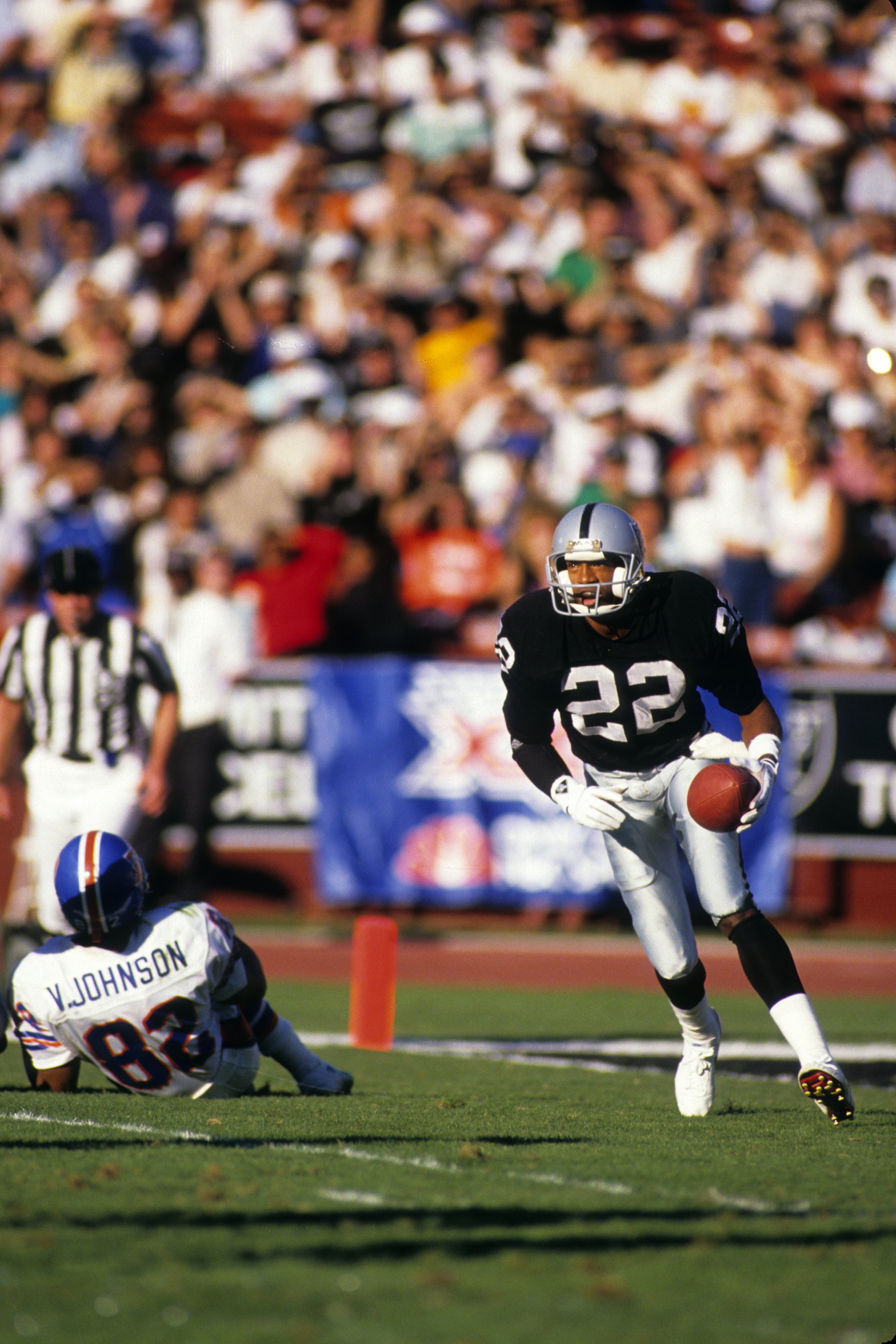 LOS ANGELES - DECEMBER 4:  Defensive back Mike Haynes #22 of the Los Angeles Raiders looks for room to run against the Denver Broncos wide receiver Vance Johnson #82 during a game at the Los Angeles Memorial Coliseum on December 4, 1988 in Los Angeles, Ca