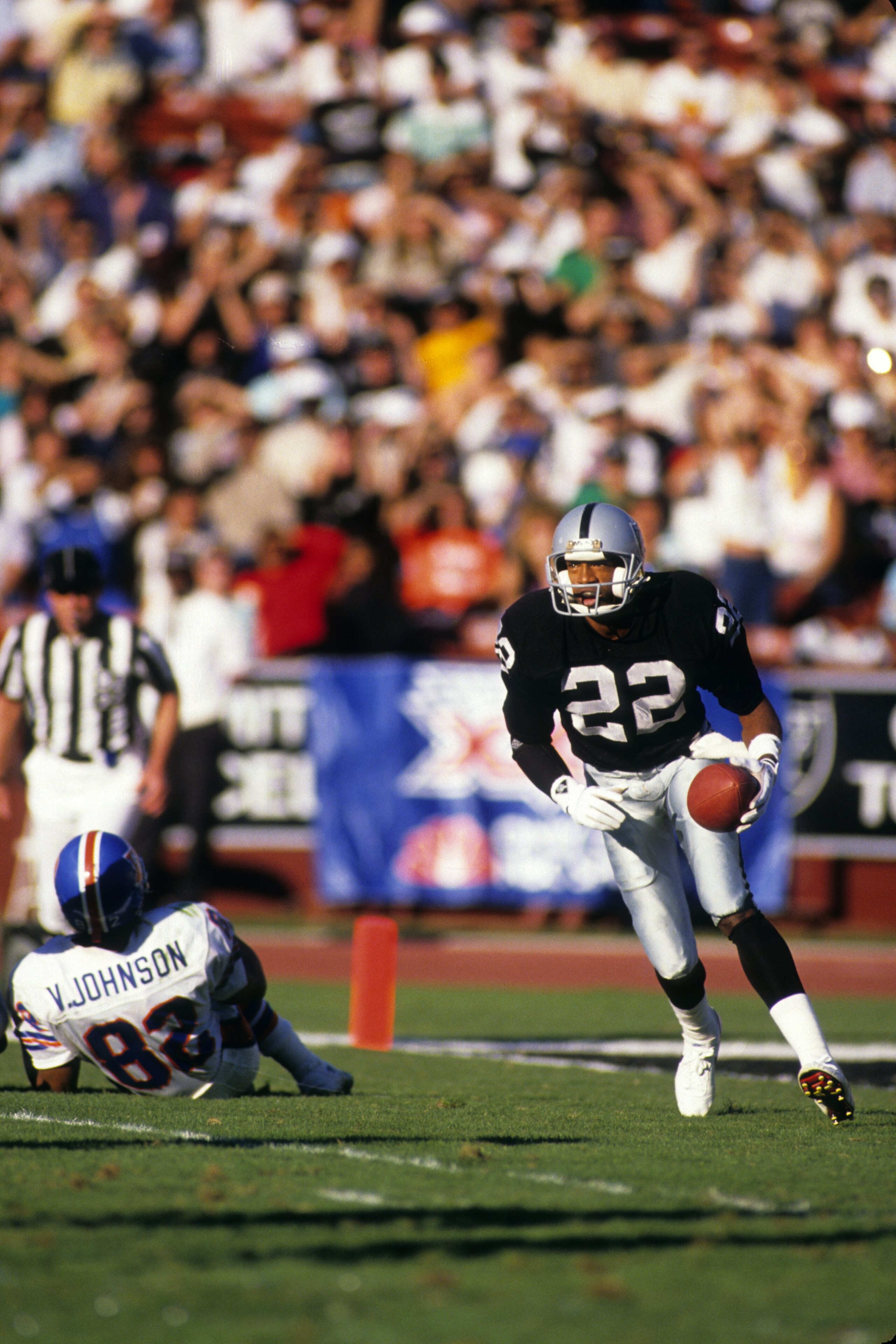 LOS ANGELES - DECEMBER 4:  Defensive back Mike Haynes #22 of the Los Angeles Raiders looks for room to run against the Denver Broncos wide receiver Vance Johnson #82 during a game at the Los Angeles Memorial Coliseum on December 4, 1988 in Los Angeles, Ca