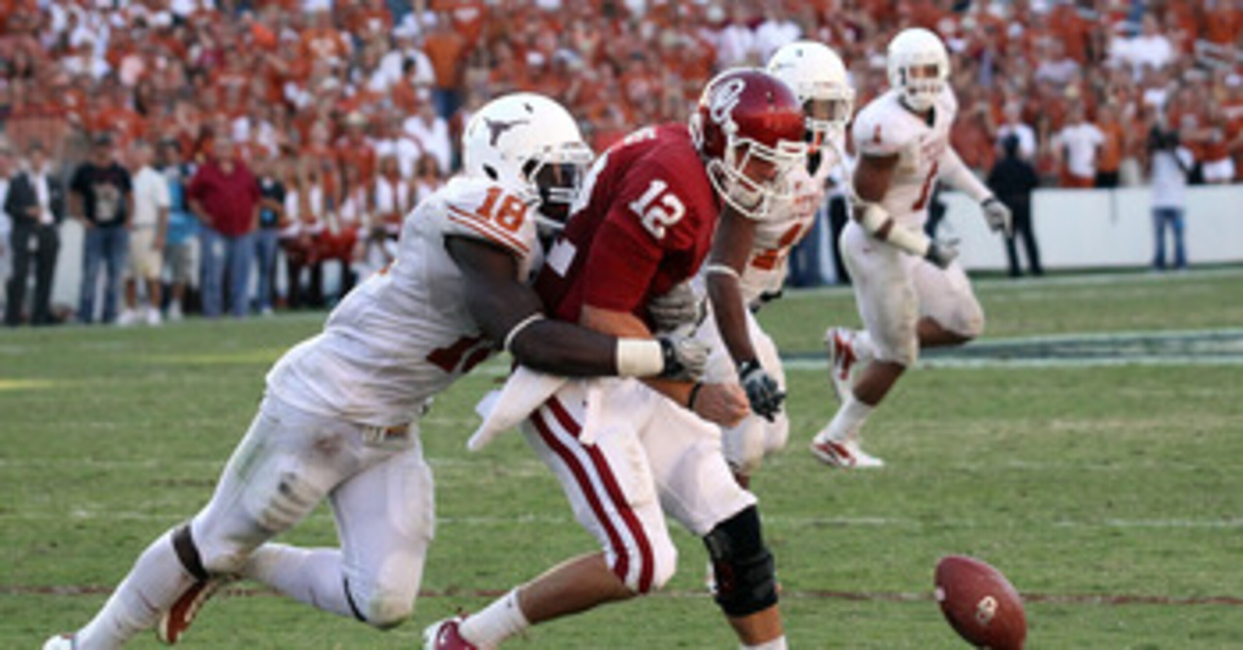 DALLAS - OCTOBER 02:  Quarterback Landry Jones #12 of the Oklahoma Sooners fumbles the ball against D.J. Grant #18 of the Texas Longhorns in the fourth quarter at the Cotton Bowl on October 2, 2010 in Dallas, Texas.  (Photo by Ronald Martinez/Getty Images