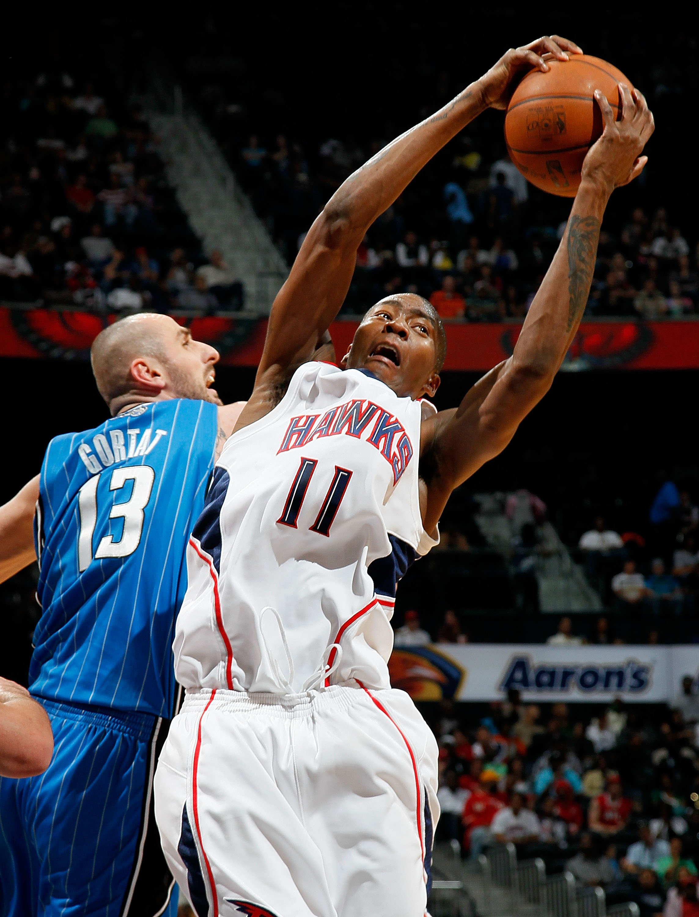 ATLANTA - MARCH 24:  Jamaal Crawford #11 of the Atlanta Hawks grabs a rebound against Marcin Gortat #13 of the Orlando Magic at Philips Arena on March 24, 2010 in Atlanta, Georgia.  NOTE TO USER: User expressly acknowledges and agrees that, by downloading