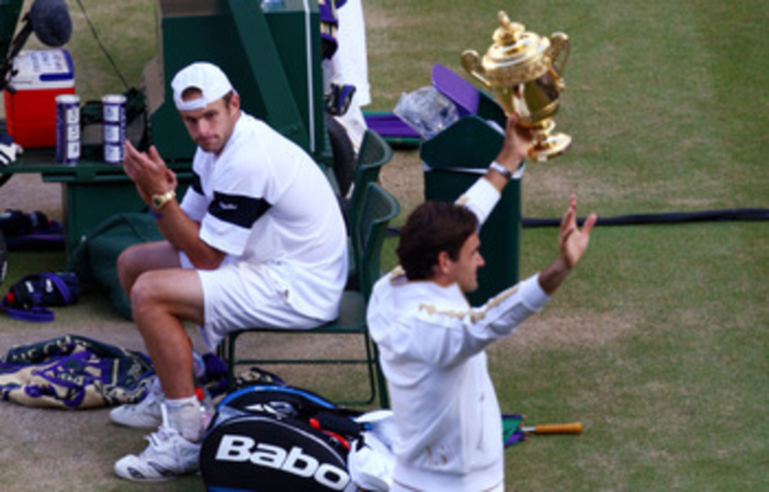 WIMBLEDON, ENGLAND - JULY 05:  Andy Roddick of USA looks despondent as Roger Federer of Switzerland celebrates with the trophy during the men's singles final match on Day Thirteen of the Wimbledon Lawn Tennis Championships at the All England Lawn Tennis a