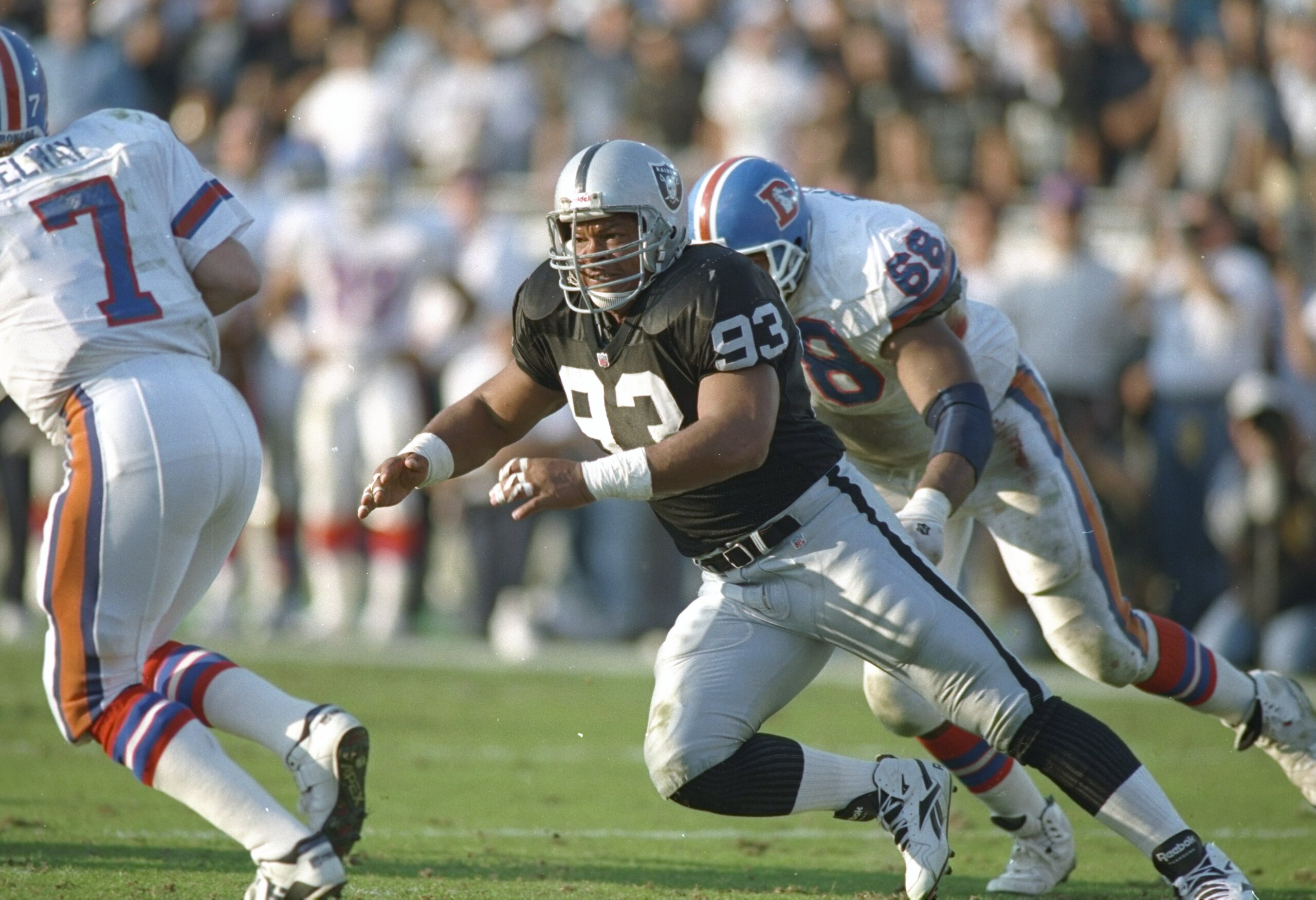 9 Jan 1994:  Defensive lineman Greg Townsend of the Los Angeles Raiders (center) goes after Denver Broncos quarterback John Elway (left) during a playoff game at the Los Angeles Memorial Coliseum in Los Angeles, California.  The Raiders won the game, 42-2
