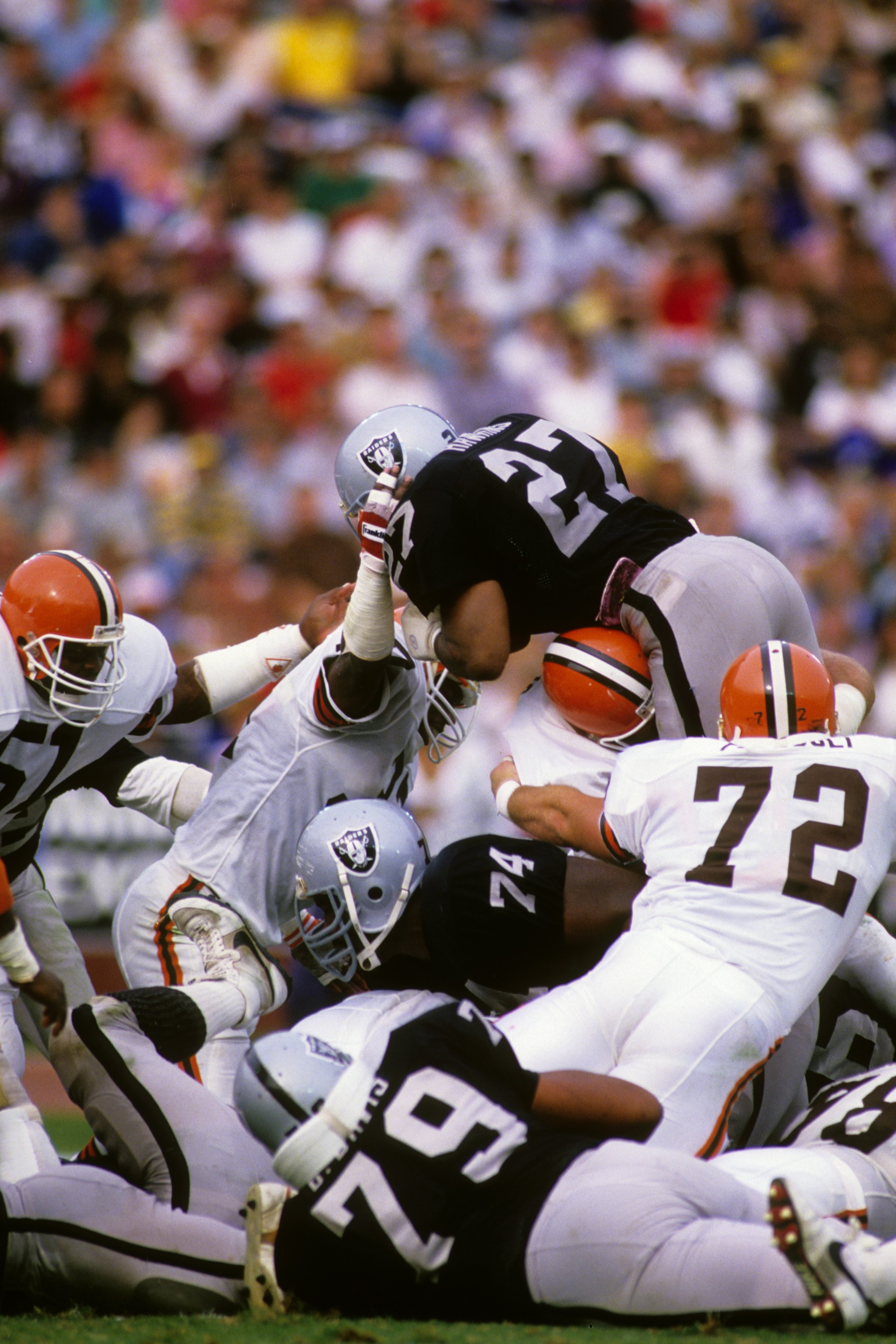 LOS ANGELES - NOVEMBER 16: Running back Frank Hawkins #27 of the Los Angeles Raiders jumps over the line of scrimmage including teammate Shelby Jordan #74 and Dave Puzzuoli #72 of the Cleveland Browns during the game at the Los Angeles Memorial Coliseum o