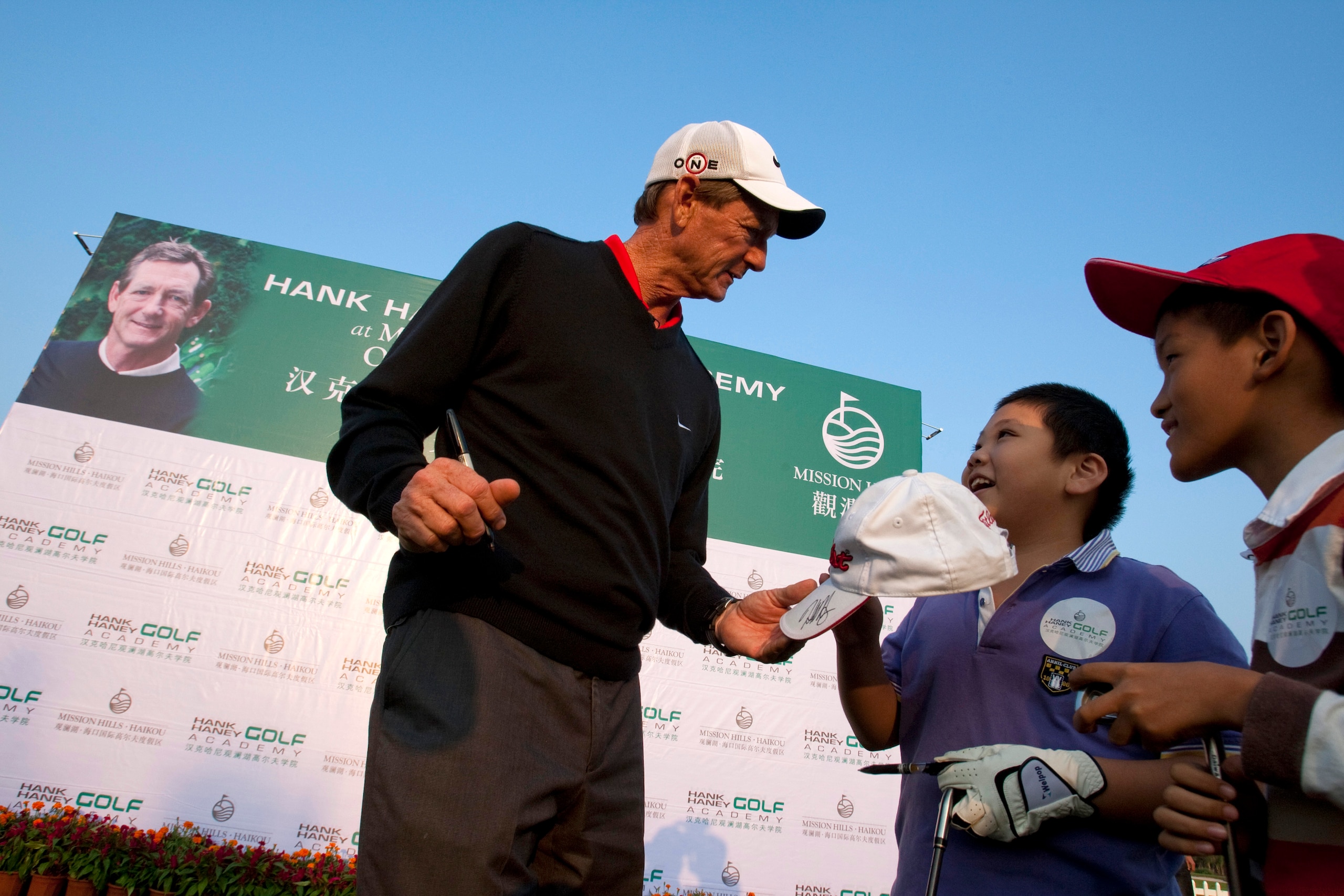 HAIKOU, CHINA - OCTOBER 28: American professional golf instructor Hank Haney (L) signs autographs for young Chinese golfers during the Hank Haney Academy opening press conference as part of the Mission Hills Star Trophy at Mission Hills Hainan on October HAIKOU, CHINA - OCTOBER 28: American professional golf instructor Hank Haney (L) signs autographs for young Chinese golfers during the Hank Haney Academy opening press conference as part of the Mission Hills Star Trophy at Mission Hills Hainan on October