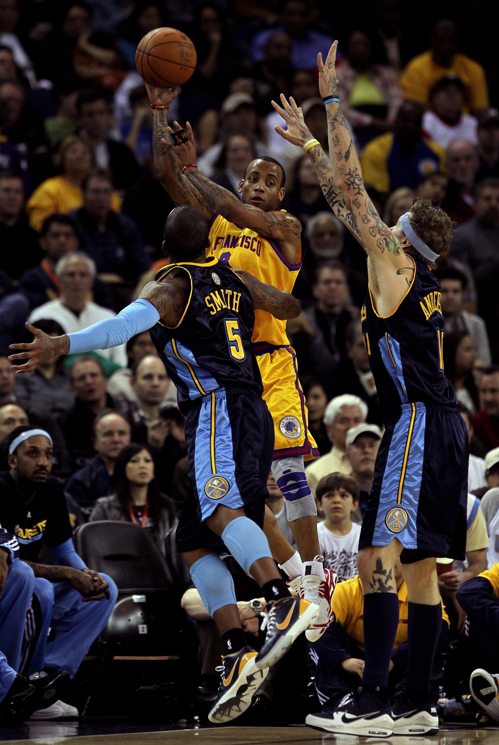 OAKLAND, CA - JANUARY 20:  Monta Ellis #8 of the Golden State Warriors passes over J.R. Smith #5 and Chris Anderson #11 of the Denver Nuggets at Oracle Arena on January 20, 2010 in Oakland, California.  NOTE TO USER: User expressly acknowledges and agrees