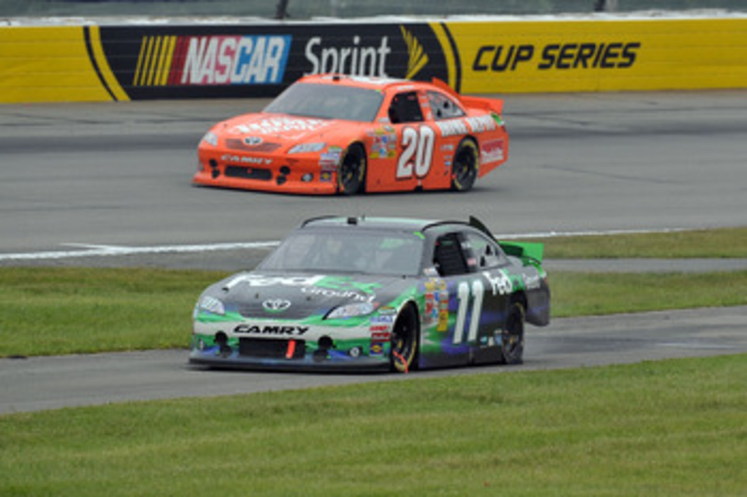 LONG POND, PA - JUNE 12:  Denny Hamlin, driver of the #11 FedEx Ground Toyota, drives down pit road with a flat rear left tire as Joey Logano, driver of the #20 The Home Depot Toyota, passes during the NASCAR Sprint Cup Series 5-Hour Energy 500 at Pocono 