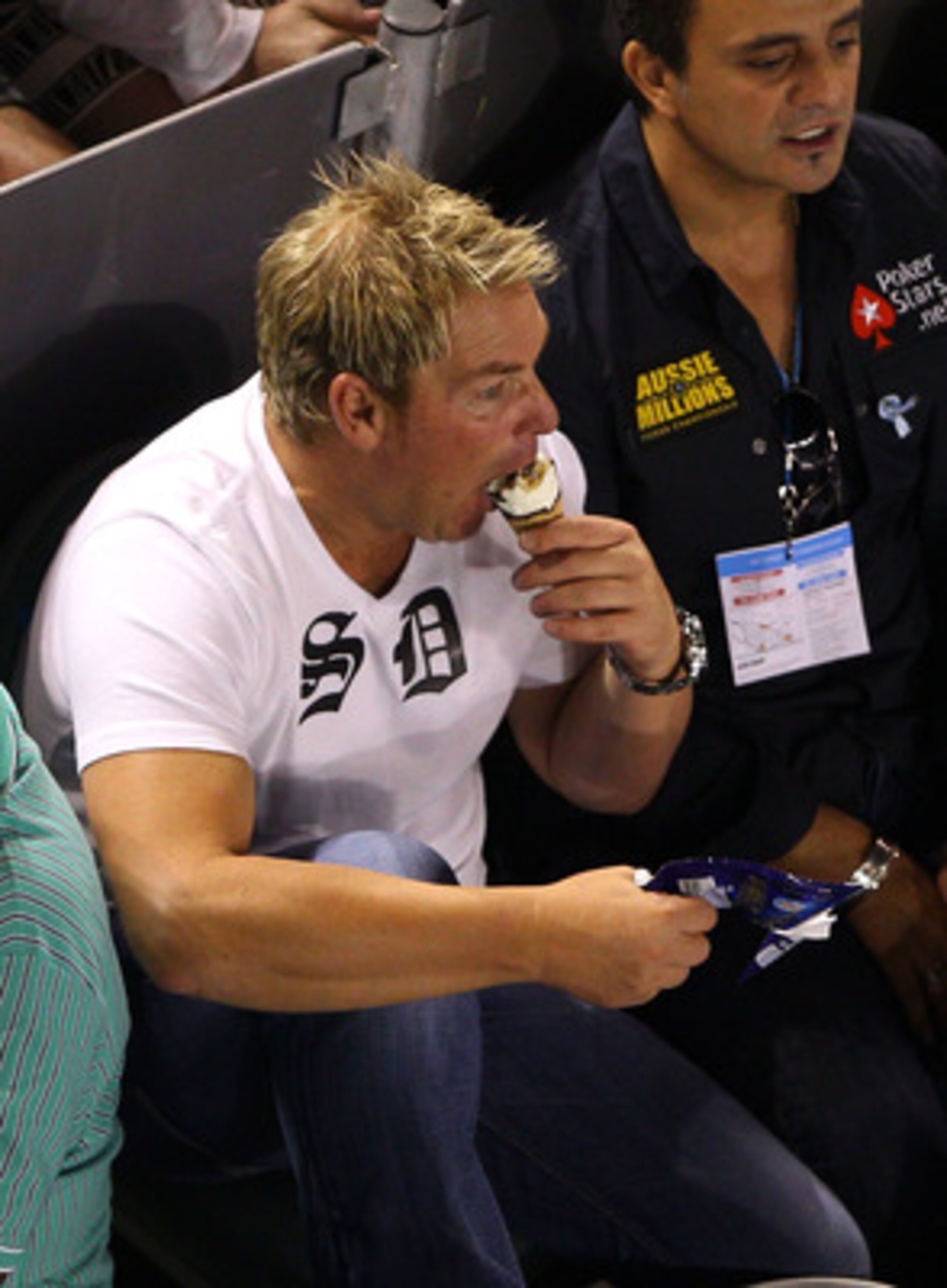 MELBOURNE, AUSTRALIA - JANUARY 23:  Former Australian cricketer Shane Warne eats a Drumstick ice cream during the fourth round match between Andy Roddick of the United States of America and Stanislas Wawrinka of Switzerland during day seven of the 2011 Au