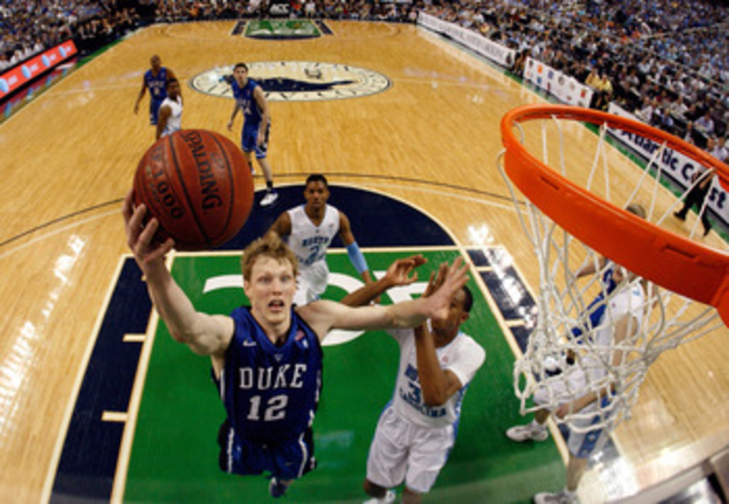 GREENSBORO, NC - MARCH 13:  Kyle Singler #12 of the Duke Blue Devils shoots against John Henson #31 of the North Carolina Tar Heels in the championship game of the 2011 ACC men's basketball tournament at the Greensboro Coliseum on March 13, 2011 in Greens