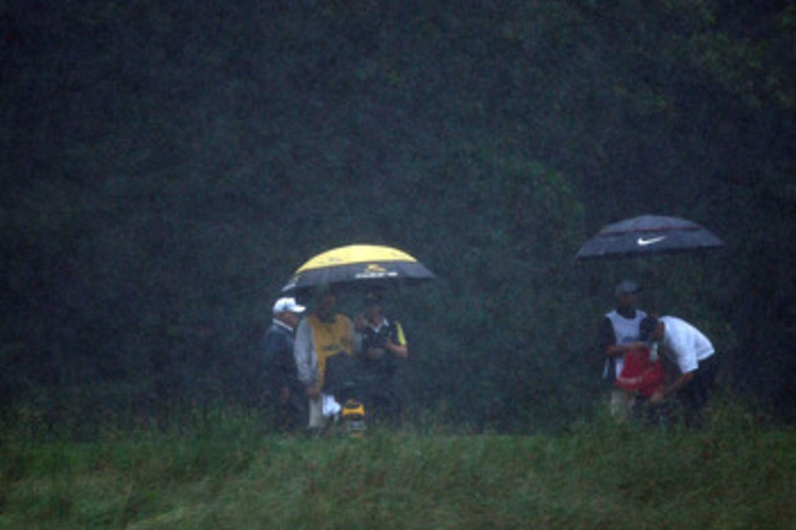 FARMINGDALE, NY - JUNE 20: Camilo Villegas of Colombia and Stewart Cink stand with their caddies under umbrellas in the rain during the third round of the 109th U.S. Open on the Black Course at Bethpage State Park on June 20, 2009 in Farmingdale, New Yor FARMINGDALE, NY - JUNE 20: Camilo Villegas of Colombia and Stewart Cink stand with their caddies under umbrellas in the rain during the third round of the 109th U.S. Open on the Black Course at Bethpage State Park on June 20, 2009 in Farmingdale, New Yor